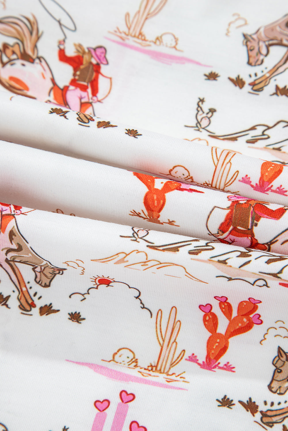 Close-up of fabric with cowboy and desert pattern.