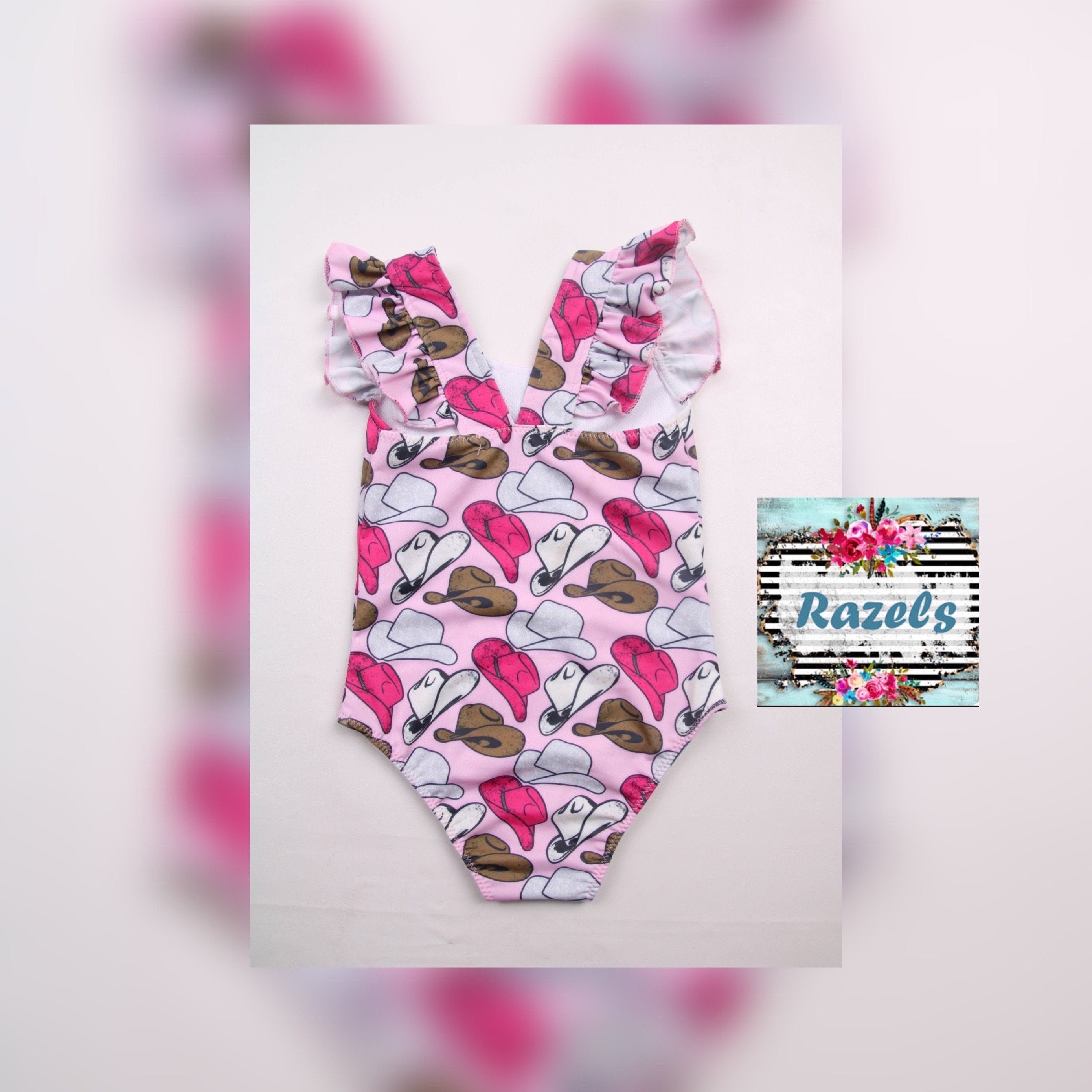 FLAT LAY AGAINST WHITE Cowgirl Swimsuit | Pink Cowgirl Hat Swimsuit | Western Swimsuits Girls, Sweetheart of the Rodeo
The cutest Cowgirl Swimsuit is here! Featuring hot pink, silver, and brown cowgirl hats on a bubblegum pink background, this one-piece swimsuit is a must-have for little rodeo queens. The flutter neckline adds the perfect touch of sweetness, making it as adorable as it is stylish!
Ships FREE FROM MONTANA with any $35+ purchase!