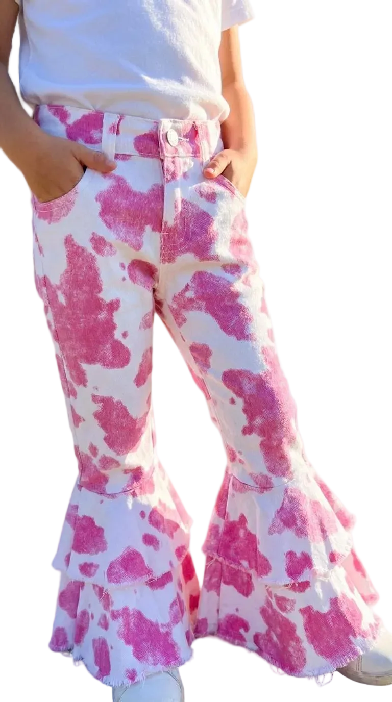 Pink and white cow print flare jeans with a tiered ruffle hem, shown on a child wearing a white t-shirt against a white background.