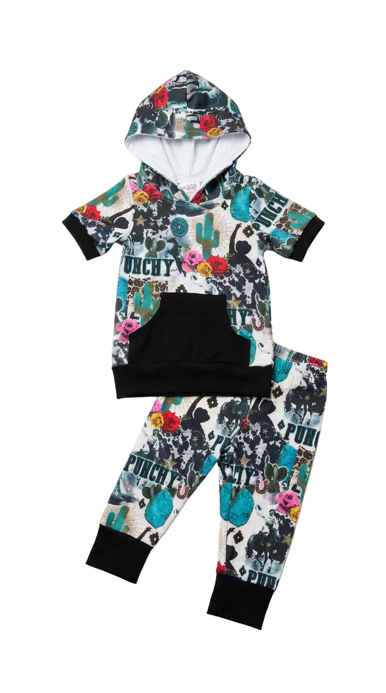 A toddler's two-piece hooded sweatshirt and jogger pants set with a colorful WESTERN-style print, black ribbed cuffs and hem, and a black front kangaroo pocket, laid flat on a light WHITE background.