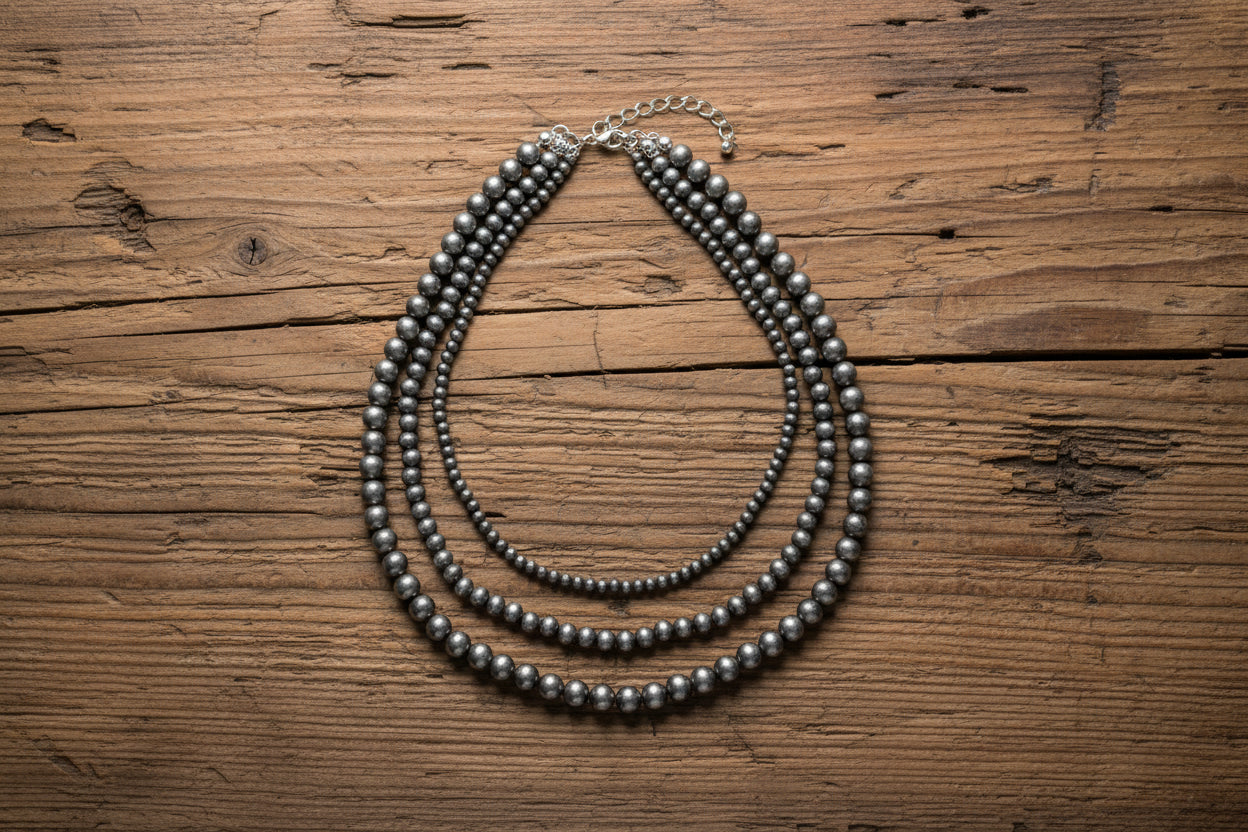 Set of beaded necklaces on a wooden surface with fur in the background
