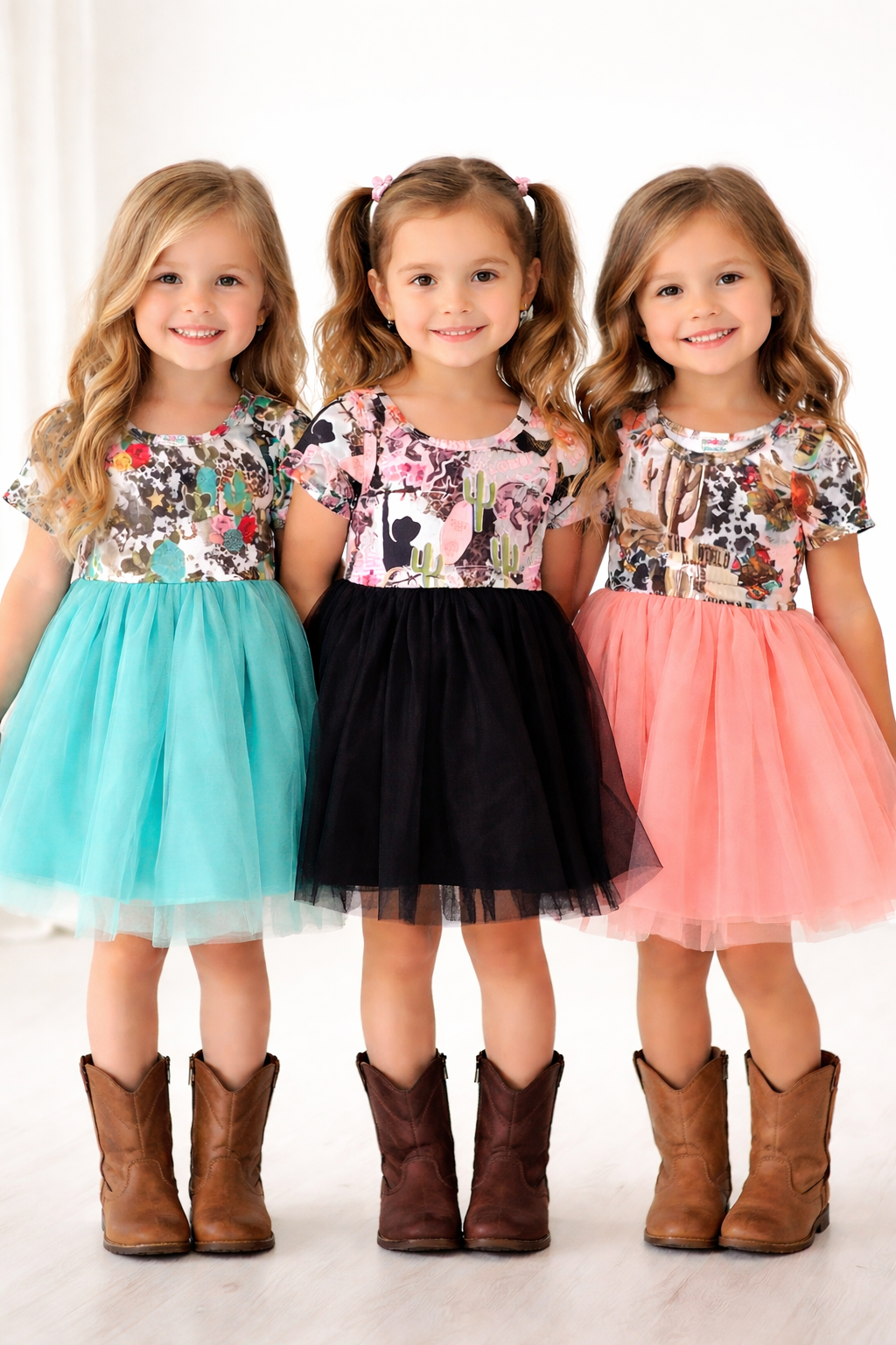 Three young girls wearing WESTERN PRINT tops and tutu skirts with cowboy boots on a white background