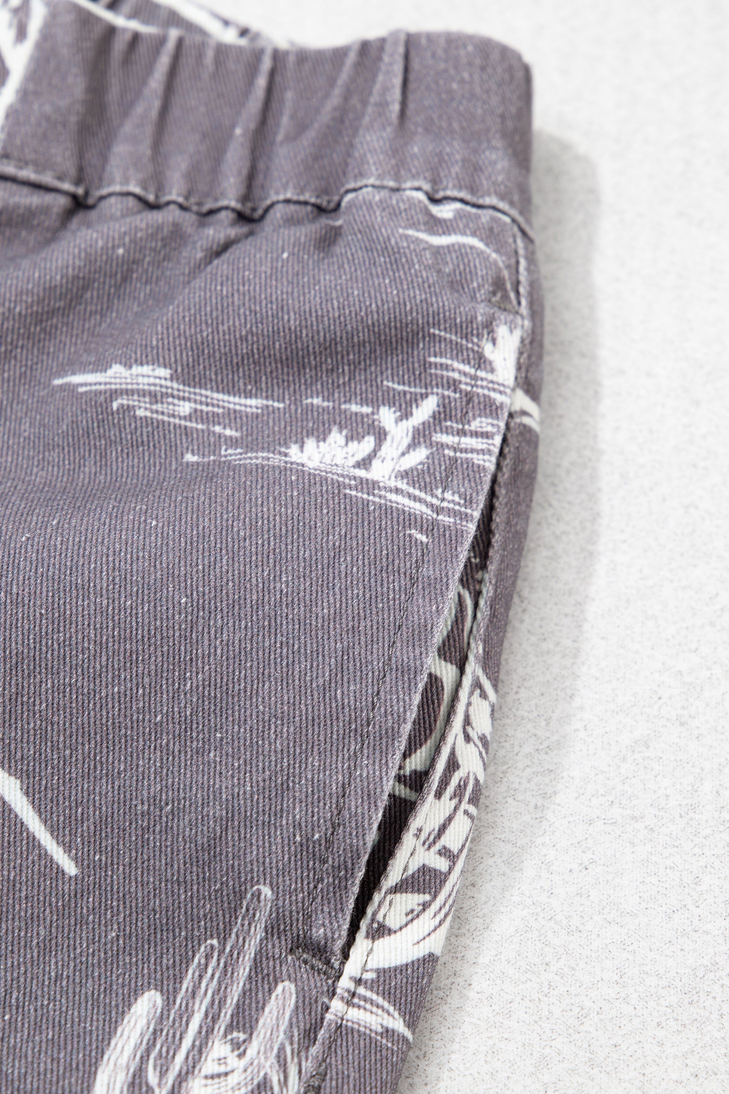 Close-up of gray pants with white patterns on a light background