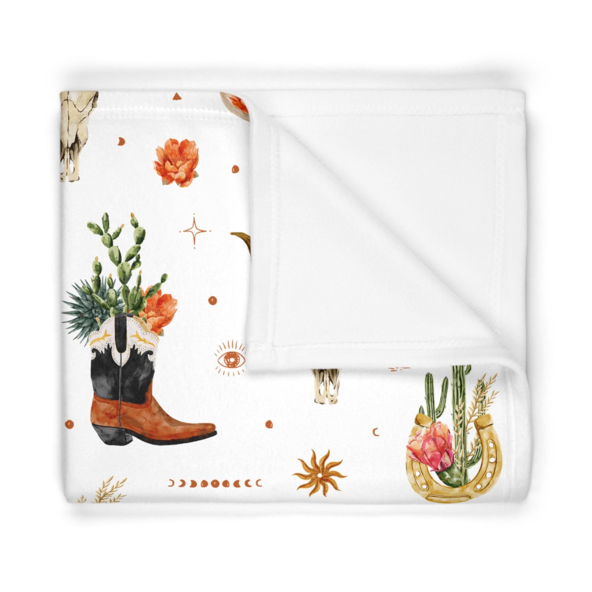 Floral and nature-themed blanket with cowboy boot, cactus, and horseshoe design on a white background