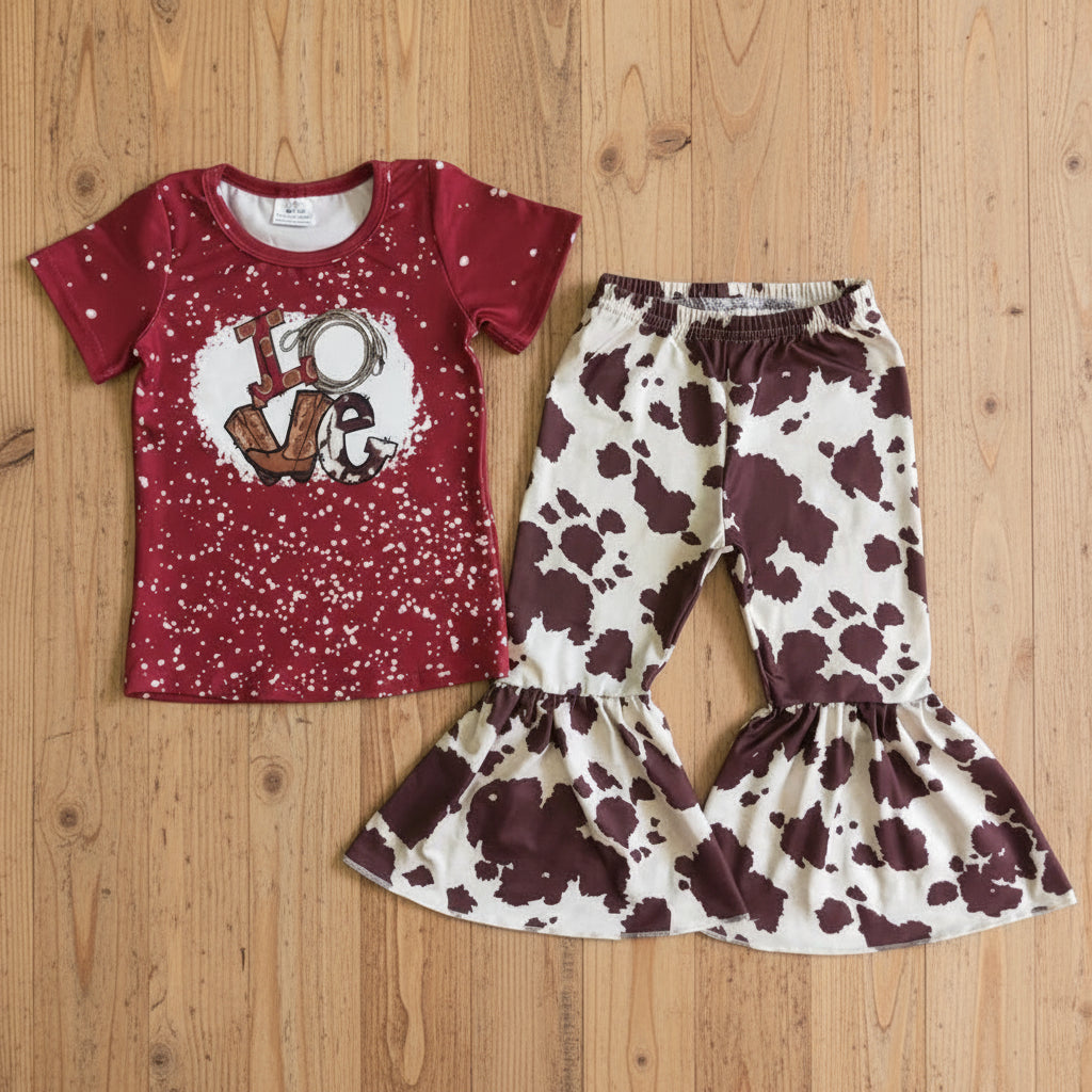 Red shirt with white splatter design and brown and white patterned pants on a textured surface