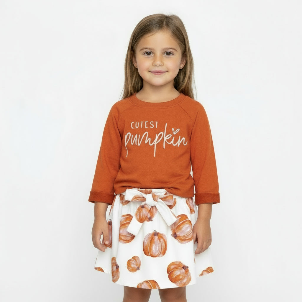 Children's outfit with orange 'Cutest Pumpkin' shirt and pumpkin-patterned skirt on a light gray background
