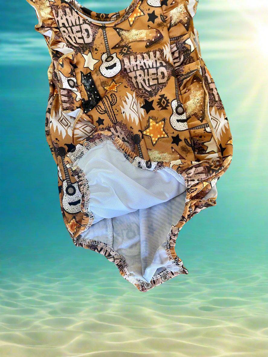High quality, matching WESTERN swimsuits for kids, featuring Mama Tried print with allover Mama Tried, Cacti, Arrows, Stars and Guitars in a country brown. Sibling Swimwear is available in boys swim trunks and girls ruffle bathing suit.