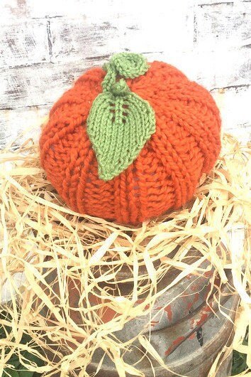 handknit large pumpkin with knit ribs along side, and a handknit leaf and vine sprouting from top! Cute!