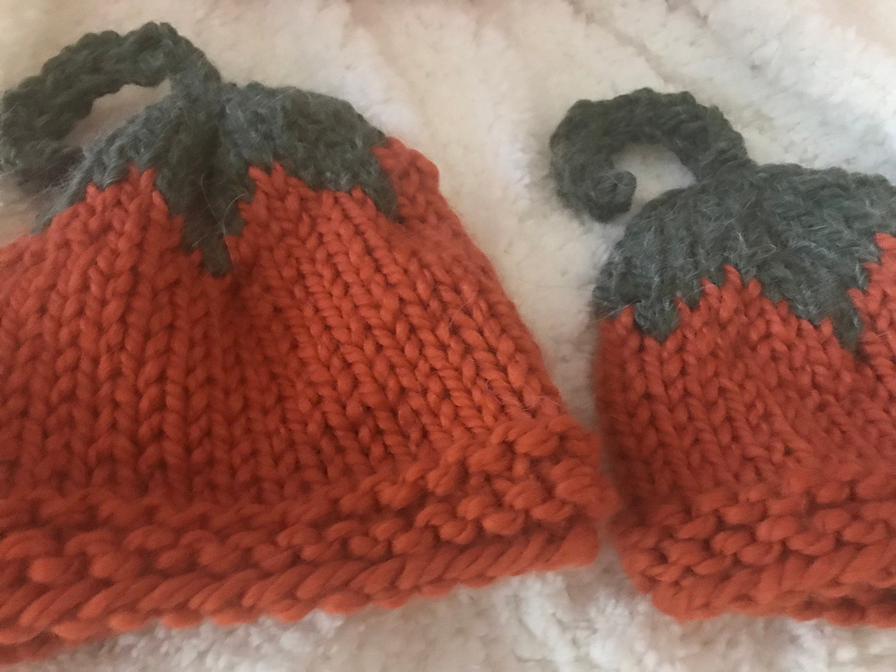Hand-knit pumpkin hat is orange with a green top ending in a pumpkin vine! ๐