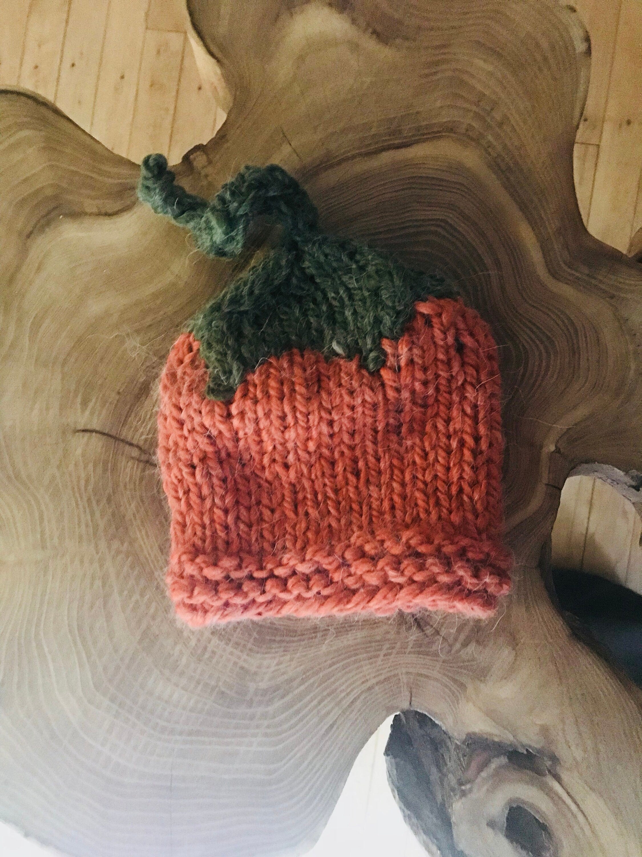 Baby Jernie wearing her handknit pumpkin hat sitting next to a Big pumpkin! Hand-knit pumpkin hat is orange with a green top ending in a pumpkin vine! ๐