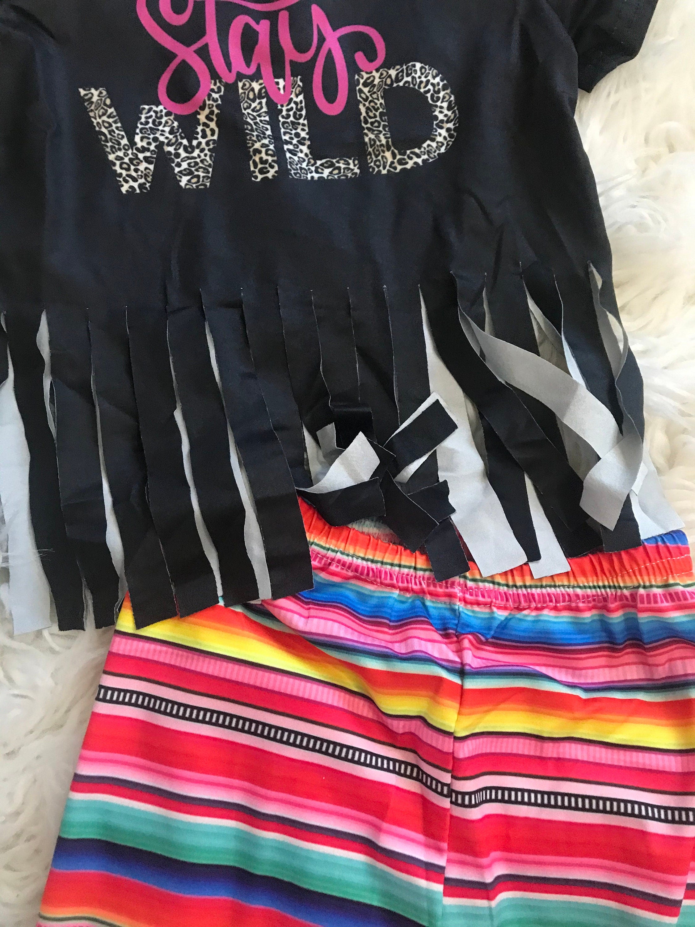 Stay Wild Girls Bell Bottom Set. Features a black Fringed Shirt with a bold "Stay Wild" design in pink and cheetah print, perfectly paired with vibrant serape-striped bell bottoms. Ships FREE with $35+ purchase.
