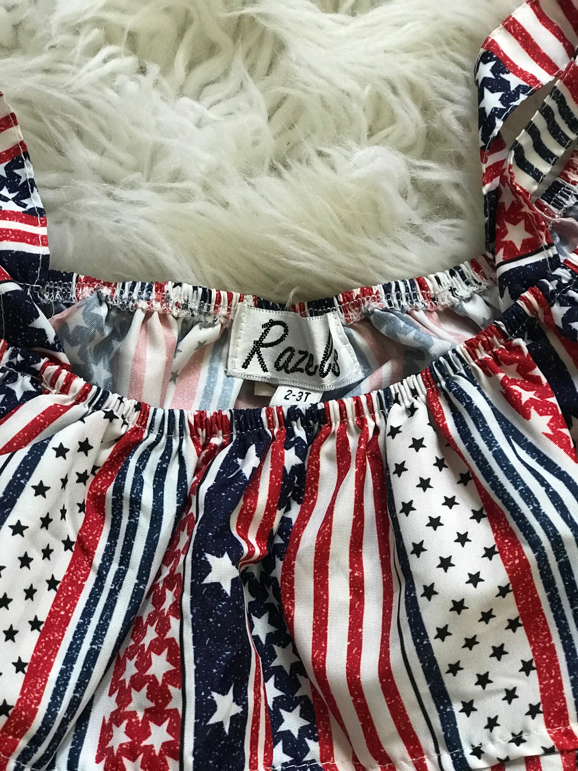 American Girl Short Outfit: The Shorts: The red, white and blue Americana pockets show through the shorts distressing! Shorts have an elastic waist and faux button.
The Shirt: features cold shoulders and an all-around ruffle in USA fabric.