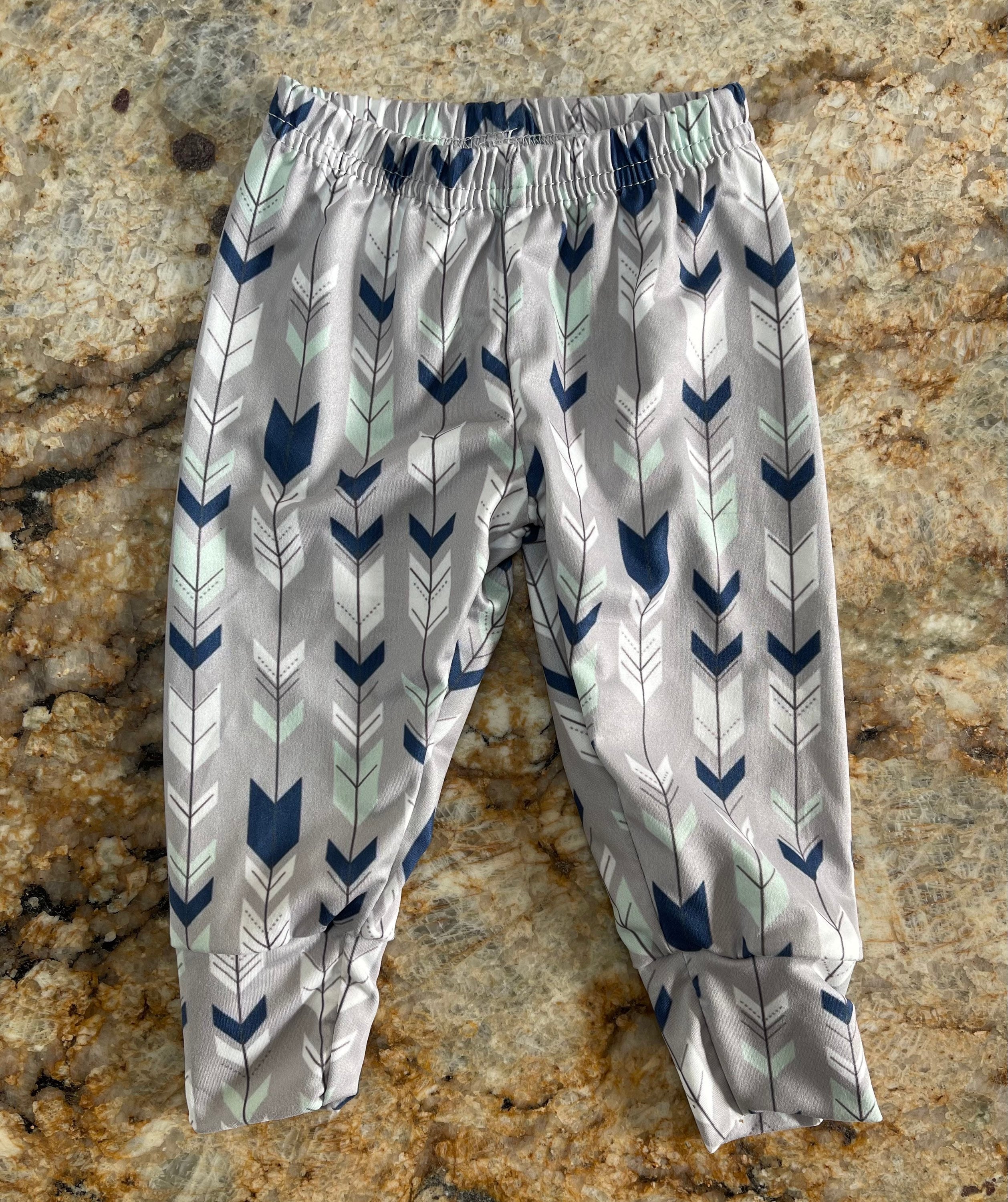 Wild One Jogger Set for Kids! Featuring a bold arrow print on the jogger pants in shades of grey, white, blue, and mint, this set is paired with a striking blue t-shirt that proudly displays "WILD" down the front. Ships FREE with $35+ purchase