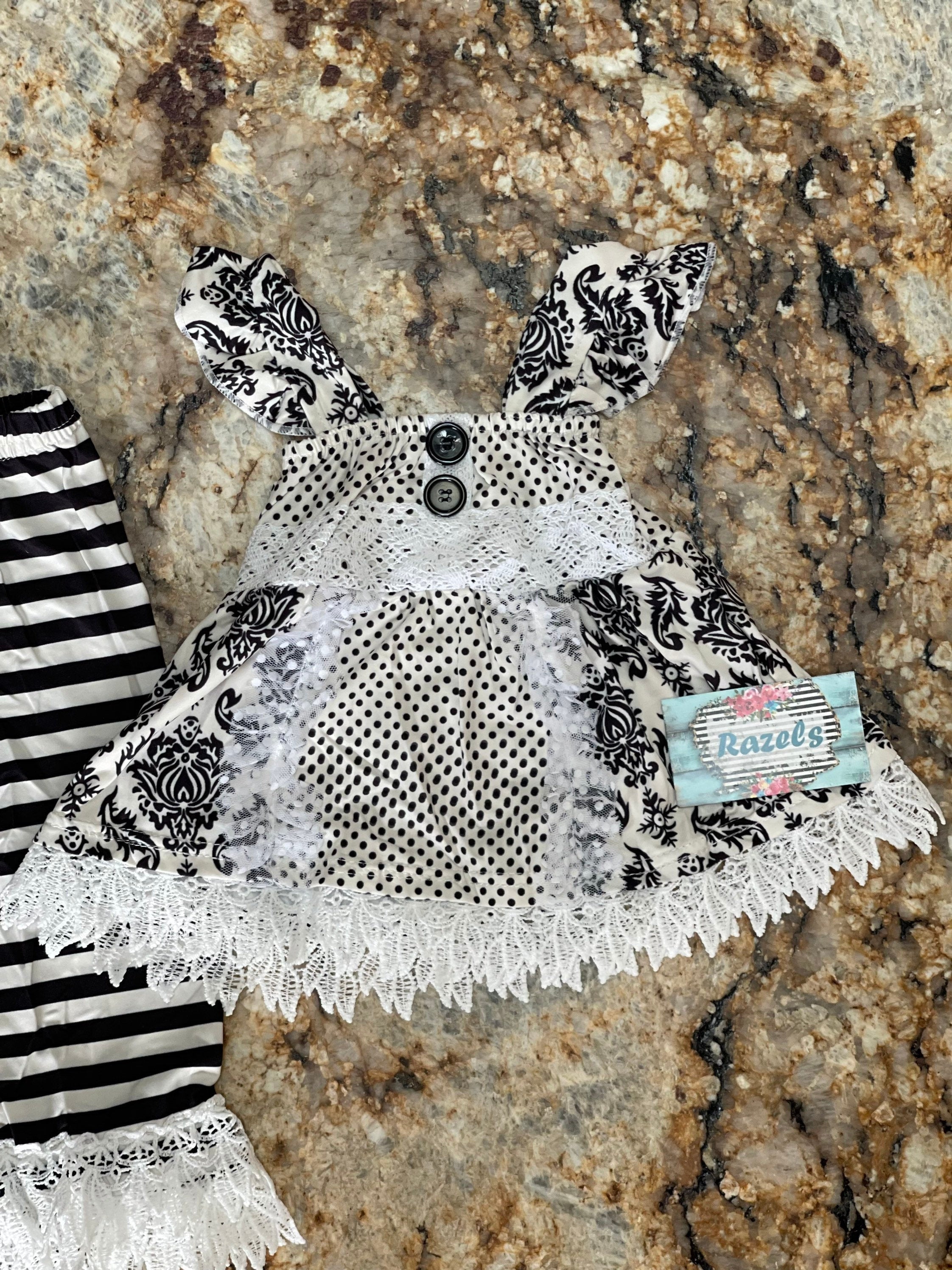 Black and White Lace Outfit – A Stunning 3-Piece Set for Little Girls. This Girls' Lace Top, Tunic Tank, and Striped Pants set is a timeless and elegant choice for special occasions. Whether for a family gathering, formal event, or a more somber occasion, this outfit is as versatile as it is stylish.
3 Piece set includes lace  ruffle shirt, tunic tank and striped pants with a lace hem. This set ships FREE from Montana with $35+ purchase from RAZELS.