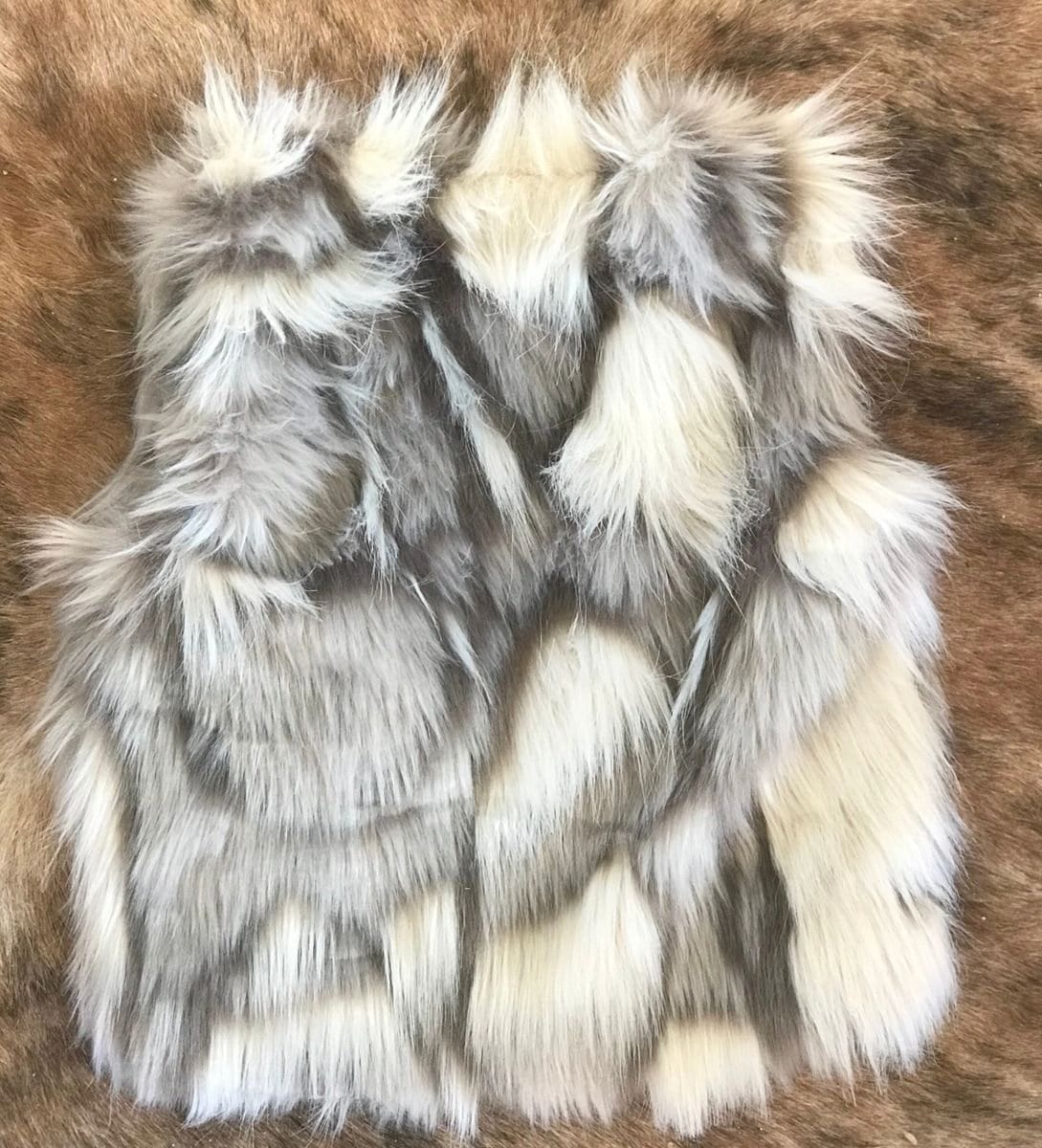 Cozy and stylish Kids' Fur Vest in a blend of grey, black, brown, and cream. Perfect for layering over any outfit, this well-made vest keeps your child warm and photo-ready. The versatile colors make it easy to mix and match with her wardrobe.