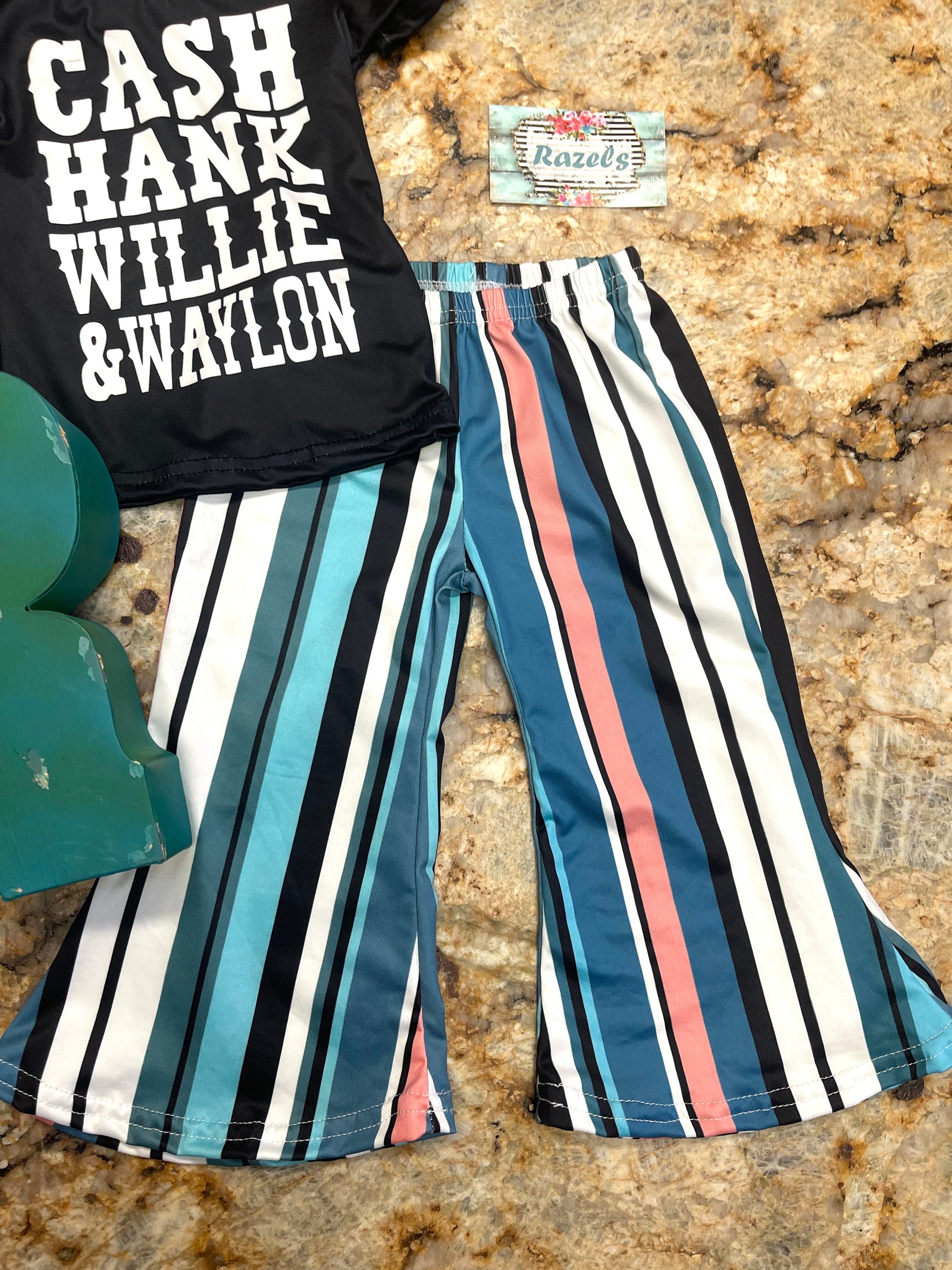 Girls Country Music bell bottom outfit. The outfit features black t-shirt with CASH, HANK, WILLIE, AND WAYLON scrolled across the front. Bell bottom pants feature stripes in pink, blue, black, white and turquoise.