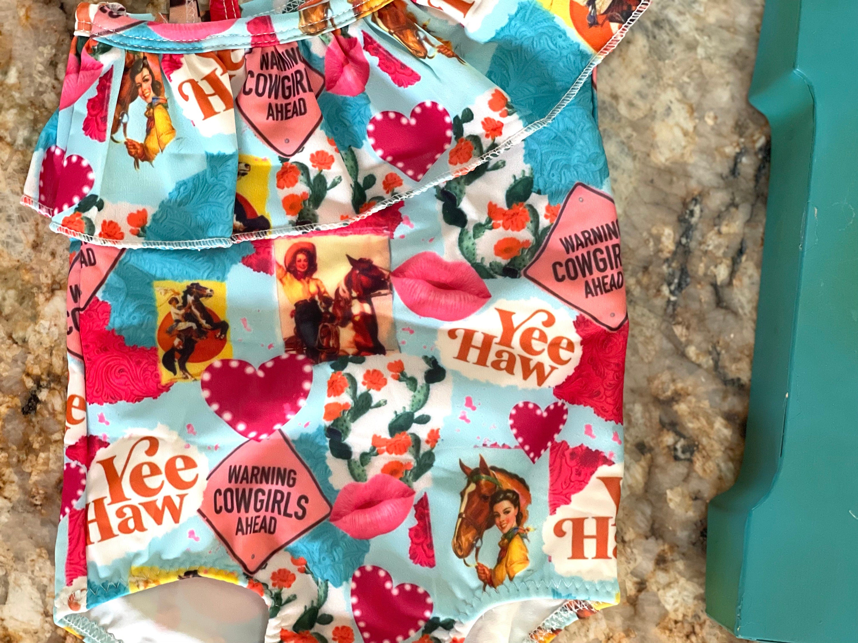 What a fun Cowgirl swimsuit!! 💗 Yeehaw!! Talk about Western Cutie! This fabulous 1-piece girls swimsuit features all the things we love about our Cowgirls - riding horses, hearts, cactus...a warning! So cute! I love this fabric so much it's also available in a girls blouse! 💞 • Available in sizes 0-3 months - 8/9!  • Double layered front More Razels! Check out all our Western swimsuits and sibling swimwear. Ships FREE with $35+ purchase.