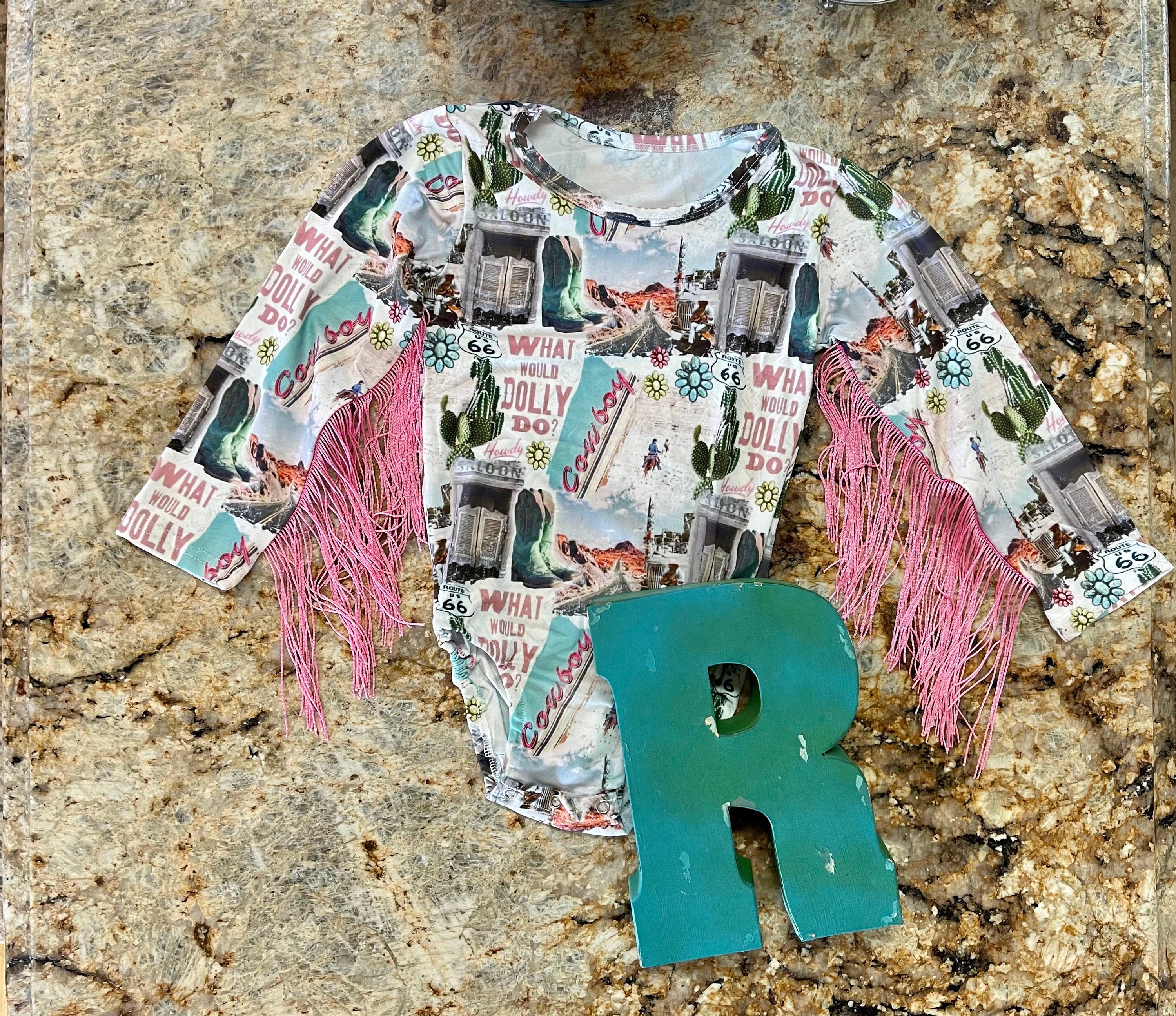 Get ready to dazzle with our adorable What Would Dolly Do? Cowgirl Shirt & Fringe Bodysuit. 
 The button-up shirt features a bold Western-inspired design, while the fringe bodysuit adds flair in vibrant pink. Shop Razels for Girls Western Wear