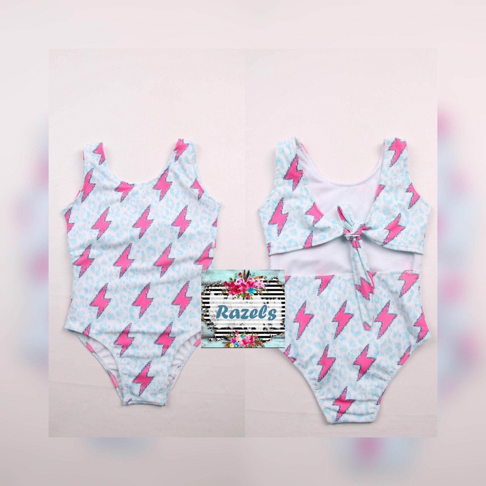 Pink Lightning Bolt One- piece Swimsuit is a Turquoise Cheetah Print One-Piece swimsuit featuring a striking pink lightning bolts and turquoise cheetah print design with a tie-back detail. Available in sizes 0/3 months to 8/9 years. Ships FREE $35+