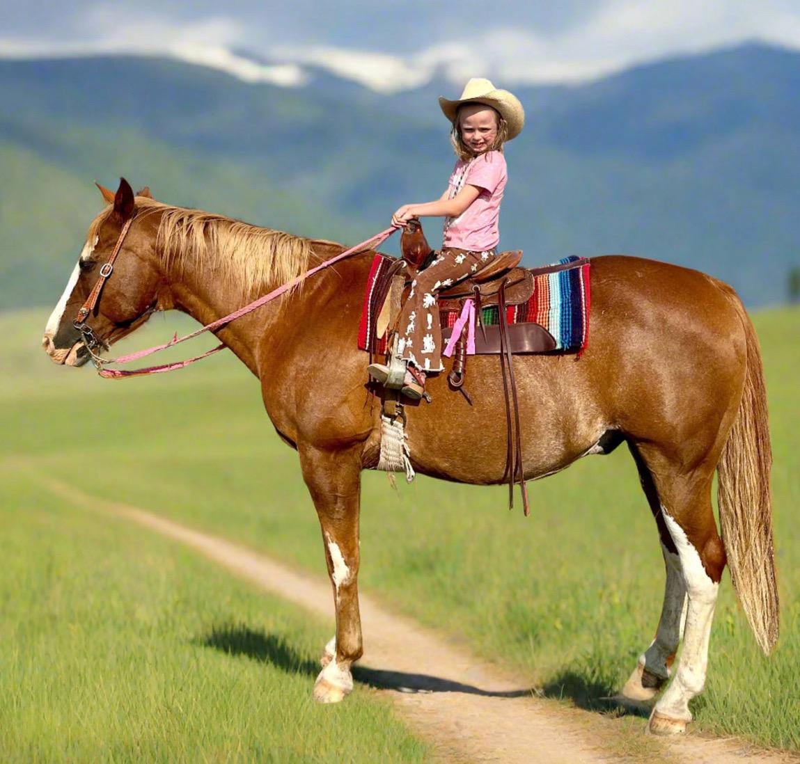 Brown Vintage Cowboy Bell Bottom Jeans featuring a vintage cowboy print, adjustable waistband, functioning pockets, and frayed bells. Styled with a matching Mama's Cowgirl T-shirt. Ideal for dressing up or down, perfect for little cowgirls."