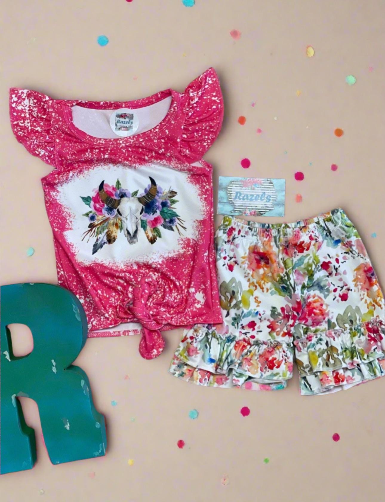 This Cowgirl BOHO Short Set is sweet, sassy, and full of Western charm — perfect for your little rodeo princess! The soft bleach-splattered ruffle sleeve tee features a bold cow skull with colorful flowers, a trendy tie-front hem, and boutique-quality detailing. Paired with matching ruffle shorts in a beautiful all-over floral print, this outfit is made for both style and play.
✓ Adorable Western boho design for girls, toddlers, and babies