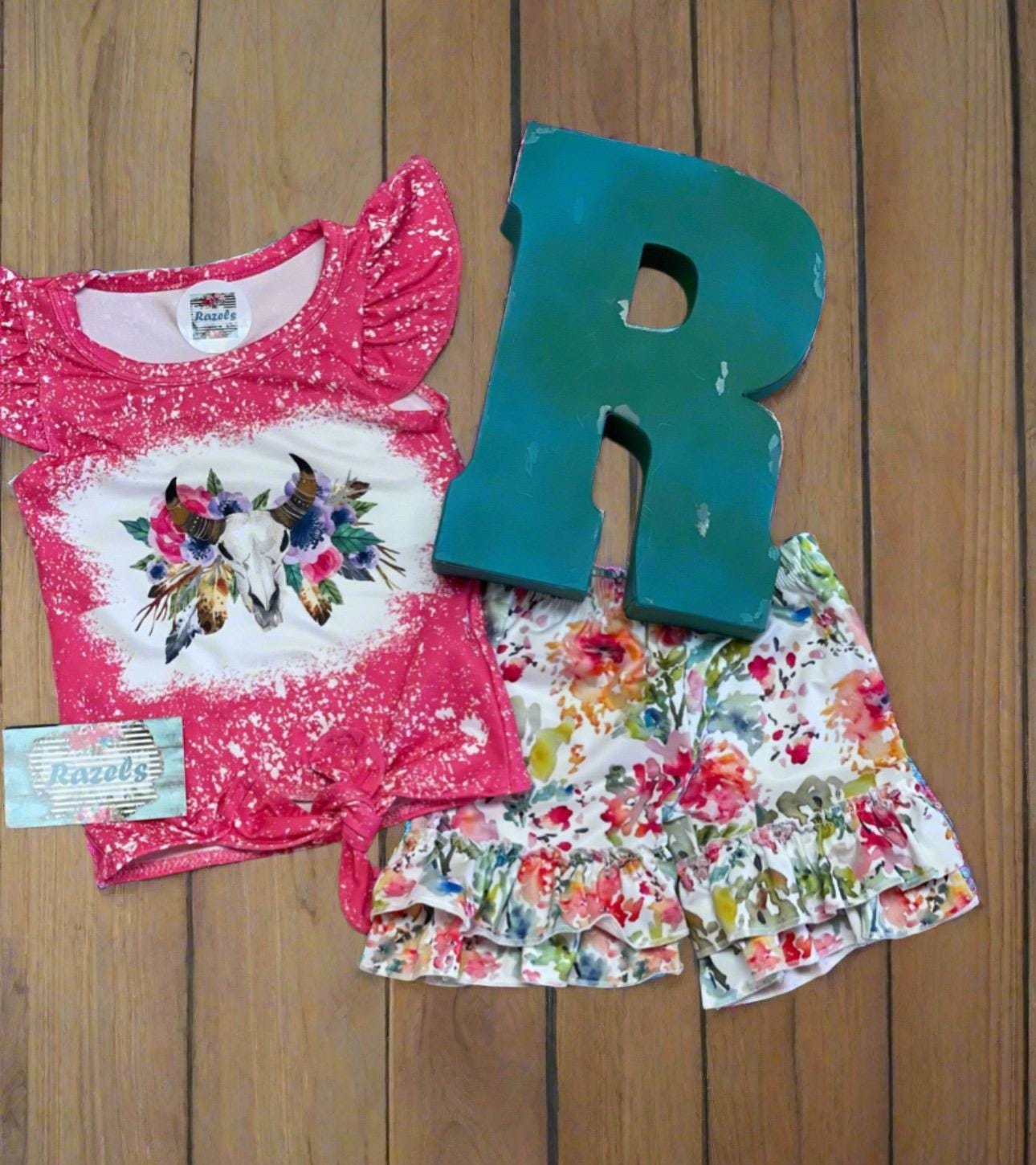 This Cowgirl BOHO Short Set is sweet, sassy, and full of Western charm — perfect for your little rodeo princess! The soft bleach-splattered ruffle sleeve tee features a bold cow skull with colorful flowers, a trendy tie-front hem, and boutique-quality detailing. Paired with matching ruffle shorts in a beautiful all-over floral print, this outfit is made for both style and play.
✓ Adorable Western boho design for girls, toddlers, and babies