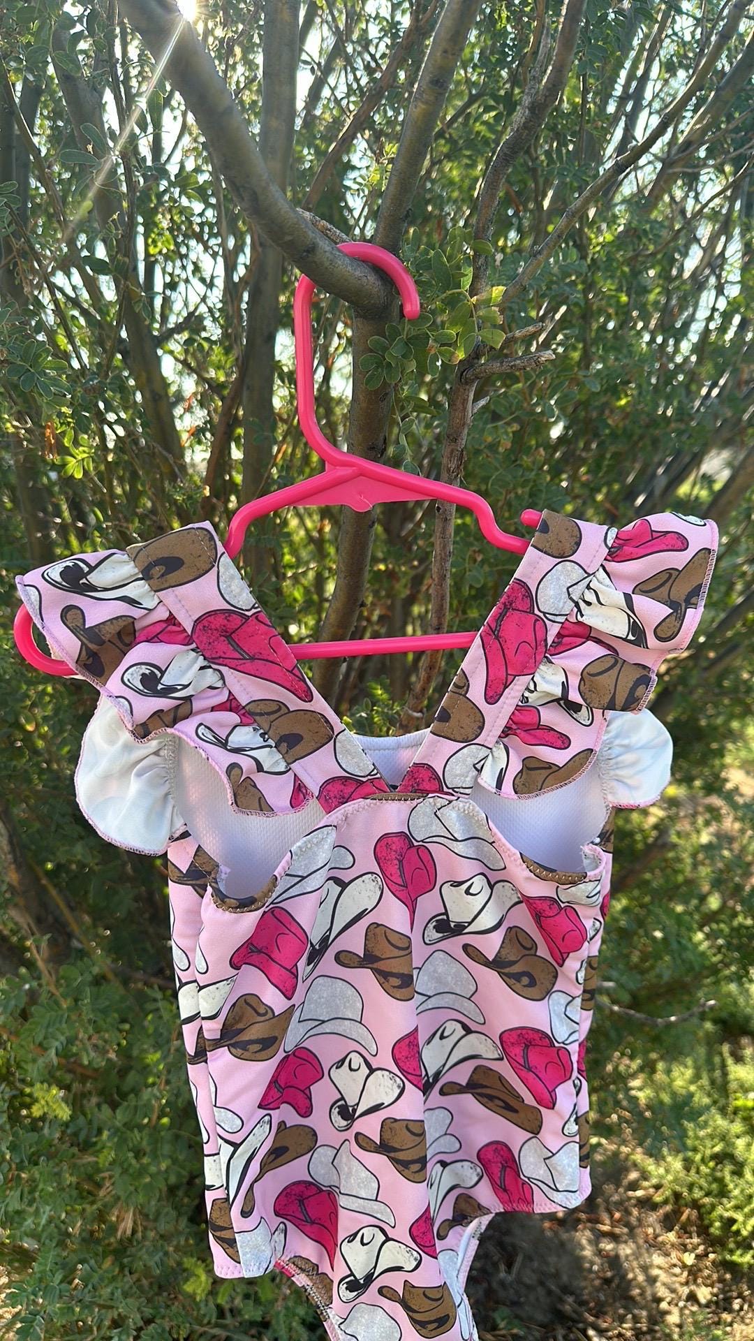 Cowgirl Swimsuit | Pink Cowgirl Hat Swimsuit | Western Swimsuits Girls, Sweetheart of the Rodeo
The cutest Cowgirl Swimsuit is here! Featuring hot pink, silver, and brown cowgirl hats on a bubblegum pink background, this one-piece swimsuit is a must-have for little rodeo queens. The flutter neckline adds the perfect touch of sweetness, making it as adorable as it is stylish!
Ships FREE FROM MONTANA with any $35+ purchase!