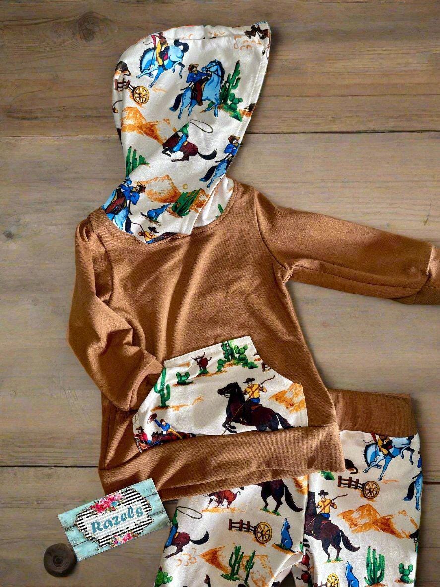 Little Cowboy Outfit – Exclusive to Razels!
Get your little cowboys ready for adventure with this Boys Western Outfit, the perfect blend of style and comfort! This playful set features a lightweight hoodie sweatshirt with a convenient kangaroo pocket and coordinating cowboy-print jogger pants. The retro cowboy design adds a fun and nostalgic vibe, making this outfit perfect for any little cowboy who loves to ride in style! 🤠 SHIPS FREE WITH $35 ORDER FROM MONTANA