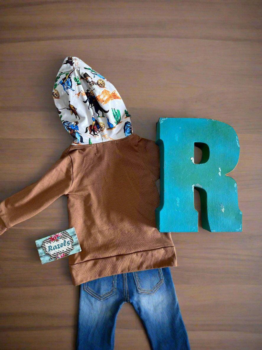 Little Cowboy Outfit – Exclusive to Razels!
Get your little cowboys ready for adventure with this Boys Western Outfit, the perfect blend of style and comfort! This playful set features a lightweight hoodie sweatshirt with a convenient kangaroo pocket and coordinating cowboy-print jogger pants. The retro cowboy design adds a fun and nostalgic vibe, making this outfit perfect for any little cowboy who loves to ride in style! 🤠 SHIPS FREE WITH $35 ORDER FROM MONTANA
