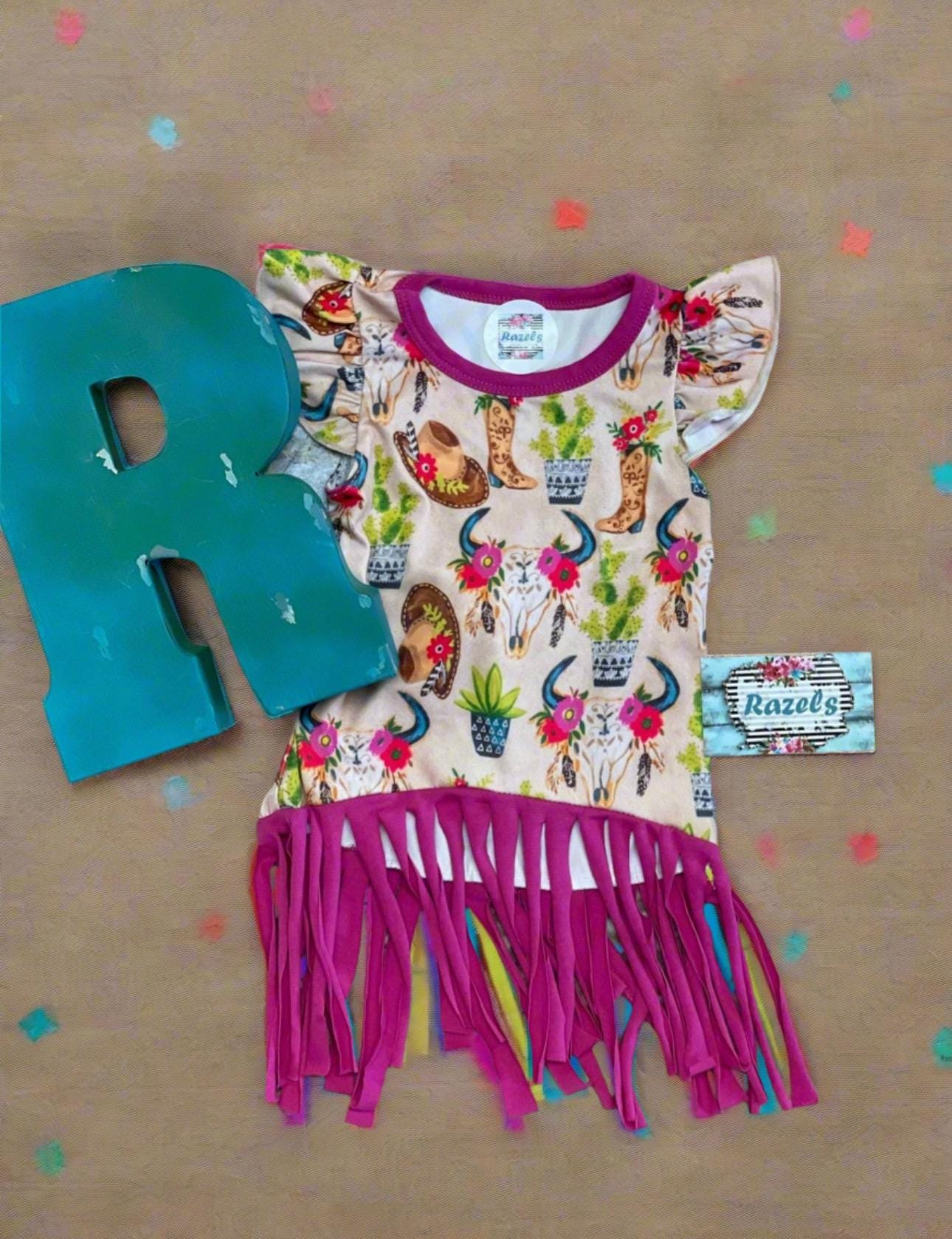 Cowgirl Fringe Dress โ The Perfect Western Tunic for Little Cowgirls features a vibrant western print, flutter sleeves, a charming tie-back, and thick pink fringe. Let your little cowgirl shine in this Cowgirl Fringe Tunic Dress!