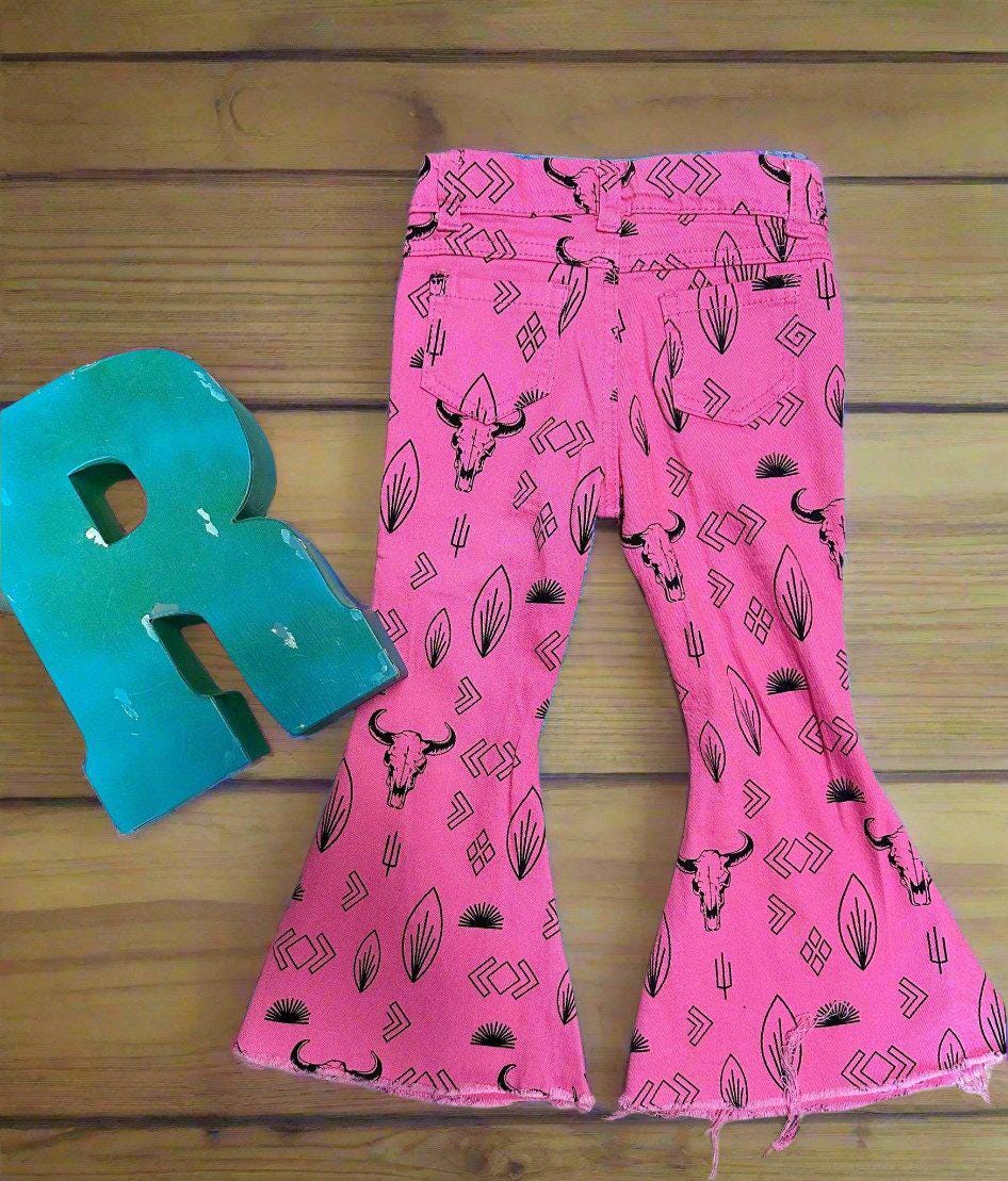 Girls Western Hot Pink Jeans. Jeans feature black steerheads, arrows, and cacti in an awesome western motif. Jeans have an adjustable waistband, pockets, and a frayed bell bottom hem.