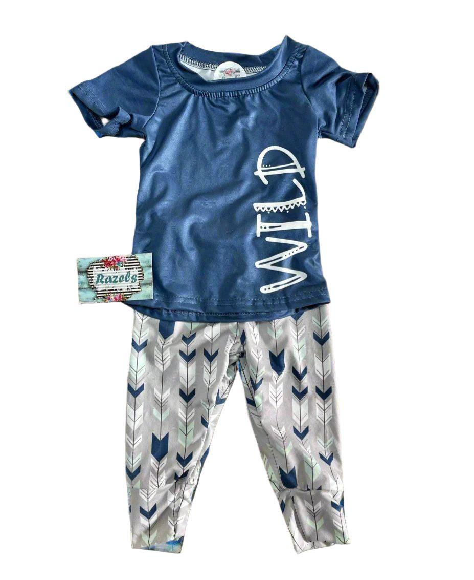 Wild One Jogger Set for Kids! Featuring a bold arrow print on the jogger pants in shades of grey, white, blue, and mint, this set is paired with a striking blue t-shirt that proudly displays "WILD" down the front. Ships FREE with $35+ purchase