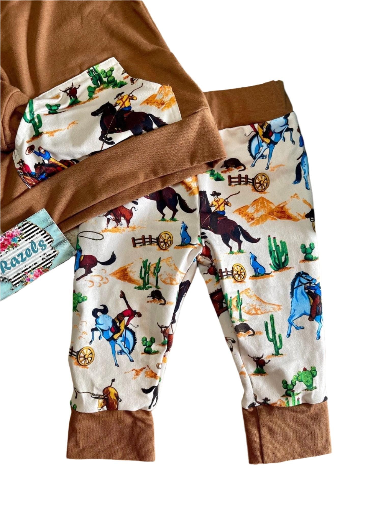 Little Cowboy Outfit – Exclusive to Razels!
Get your little cowboys ready for adventure with this Boys Western Outfit, the perfect blend of style and comfort! This playful set features a lightweight hoodie sweatshirt with a convenient kangaroo pocket and coordinating cowboy-print jogger pants. The retro cowboy design adds a fun and nostalgic vibe, making this outfit perfect for any little cowboy who loves to ride in style! 🤠 SHIPS FREE WITH $35 ORDER FROM MONTANA