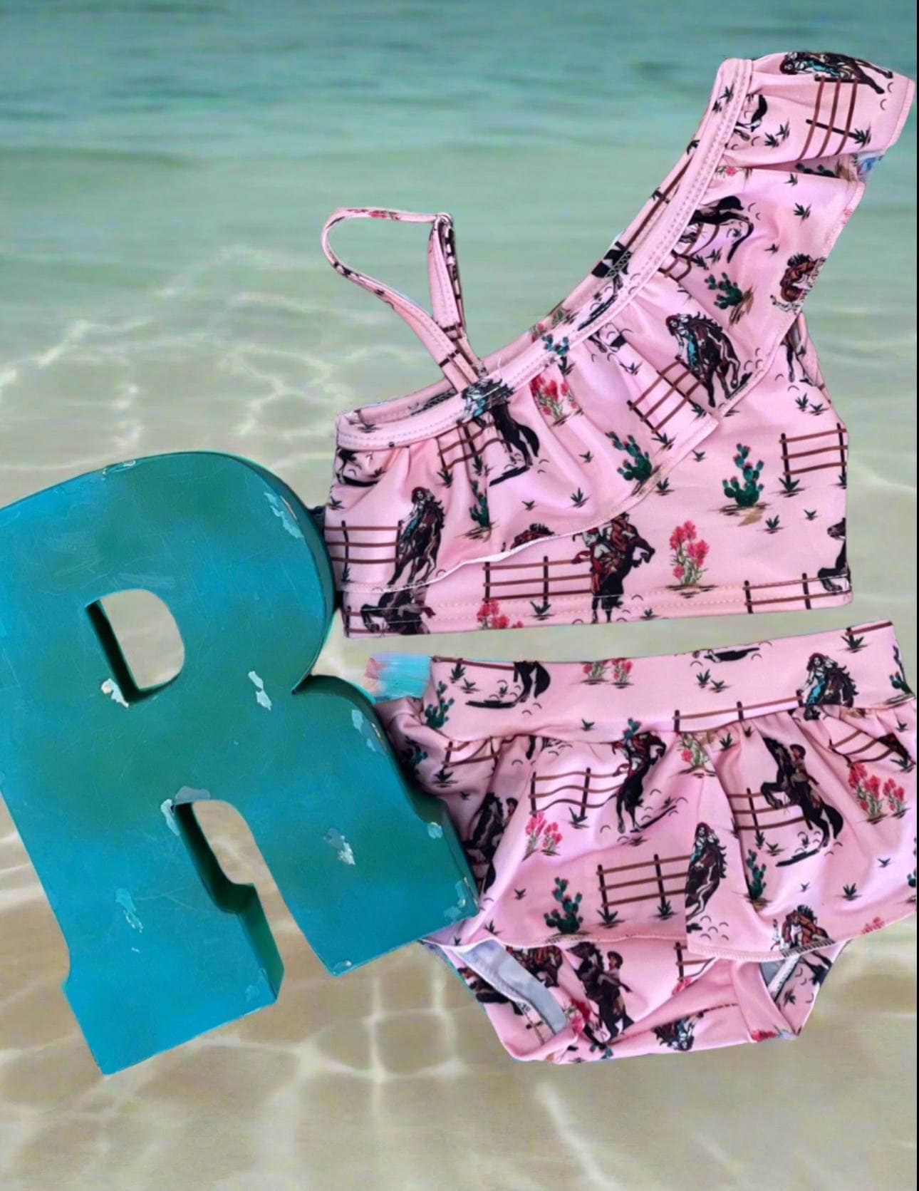 Saddle up for summer with this Pink Cowgirl Swimsuit! This Western Ruffled Swimsuit features vintage cowgirls, adorable ruffles, and a bold Wild West vibe, perfect for little adventurers. Designed for comfort and durability, it includes adjustable straps, a fully lined front, and high-quality swimsuit material. Available in sizes 0-3 months to 6/7, this Cowgirl Bathing Suit is ideal for babies and toddlers. FREE U.S. shipping on $35+ orders. Shop Razels for the best Western Bikini today!