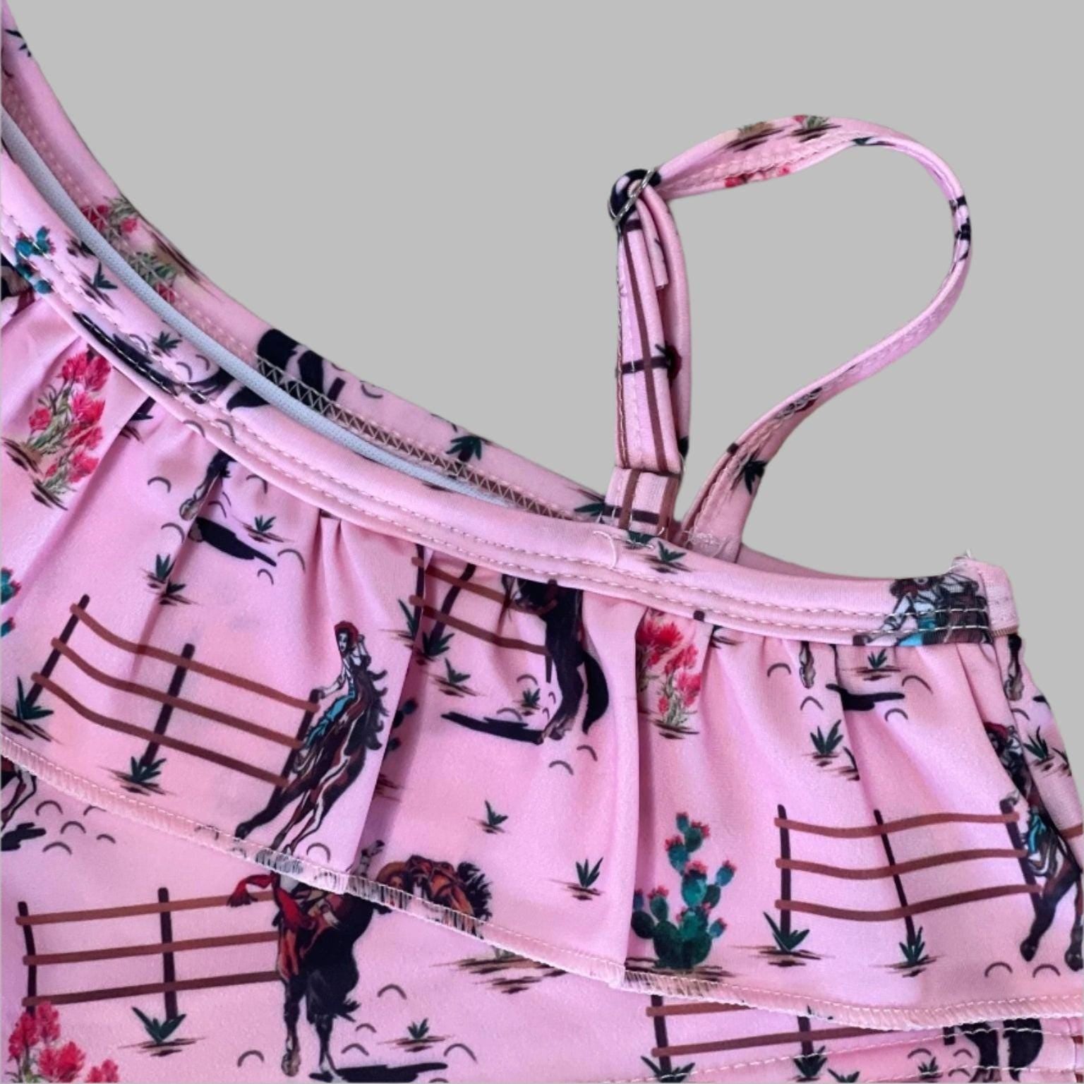 Saddle up for summer with this Pink Cowgirl Swimsuit! This Western Ruffled Swimsuit features vintage cowgirls, adorable ruffles, and a bold Wild West vibe, perfect for little adventurers. Designed for comfort and durability, it includes adjustable straps, a fully lined front, and high-quality swimsuit material. Available in sizes 0-3 months to 6/7, this Cowgirl Bathing Suit is ideal for babies and toddlers. FREE U.S. shipping on $35+ orders. Shop Razels for the best Western Bikini today!