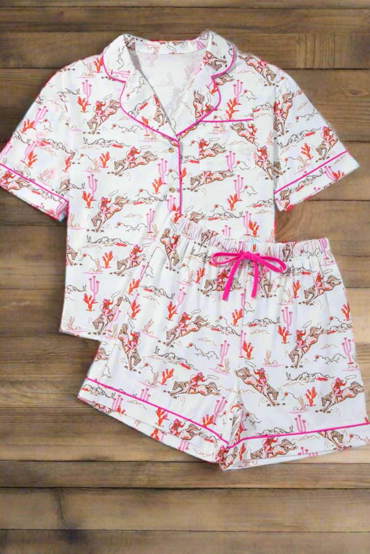 Pink Cowgirl Pajama Short Set 🩷
How fun and cowgirl-tastic is this Cowgirl Pajama Short Set?! This Western Pajama Set is the perfect blend of comfort and style, featuring a button-up top with short sleeves and matching shorts with pockets. Perfect summer cowgirl pajamas for a bridal shower or birthday gift. The playful cowgirl print showcases cowgirls doing their cowgirl thing, with hot pink piping, a drawstring, and pink and orange cacti details. SHIPS FREE from MONTANA today.