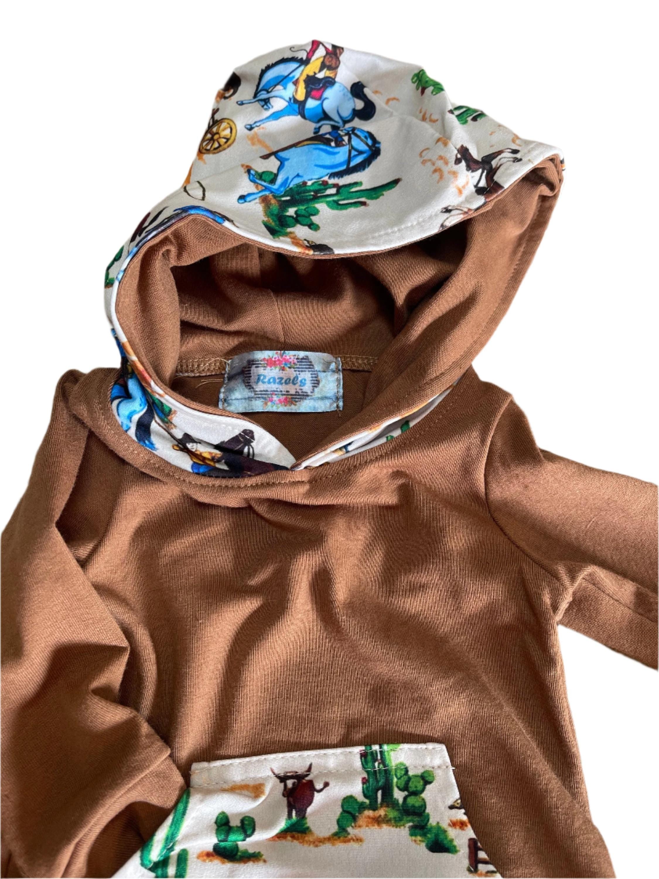 Little Cowboy Outfit – Exclusive to Razels!
Get your little cowboys ready for adventure with this Boys Western Outfit, the perfect blend of style and comfort! This playful set features a lightweight hoodie sweatshirt with a convenient kangaroo pocket and coordinating cowboy-print jogger pants. The retro cowboy design adds a fun and nostalgic vibe, making this outfit perfect for any little cowboy who loves to ride in style! 🤠 SHIPS FREE WITH $35 ORDER FROM MONTANA