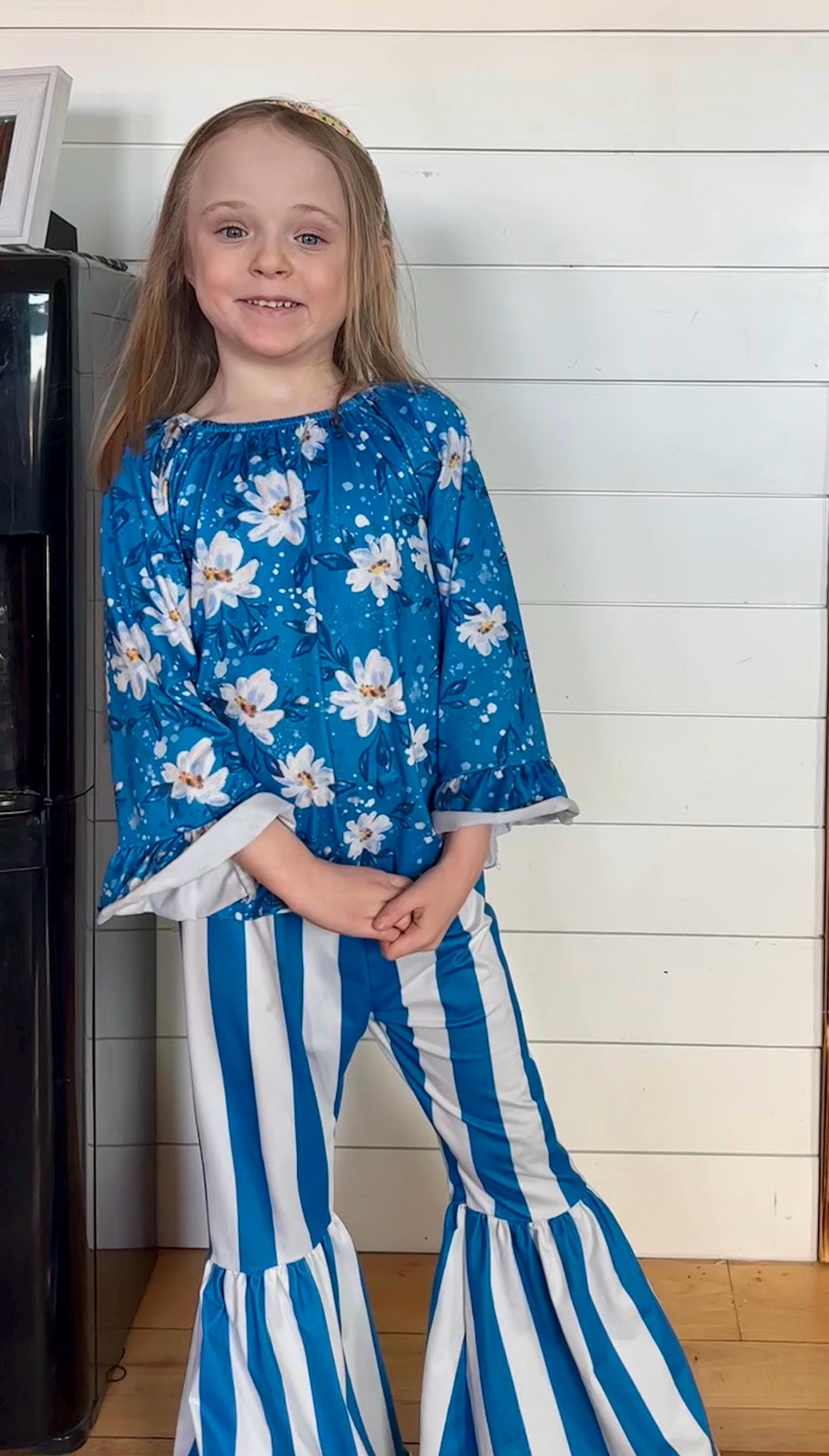 Get your little lady ready to shine this back-to-school season with our adorable Daisy Flower Blouse paired perfectly with blue and white striped bell bottom pants!
The blouse features a sweet daisy print with playful ruffled wrists that add just the right touch of charm. The bell bottoms bring a retro twist with their bold stripes and comfy stretch fabric that moves with her every step. FREE SHIPPING $35+