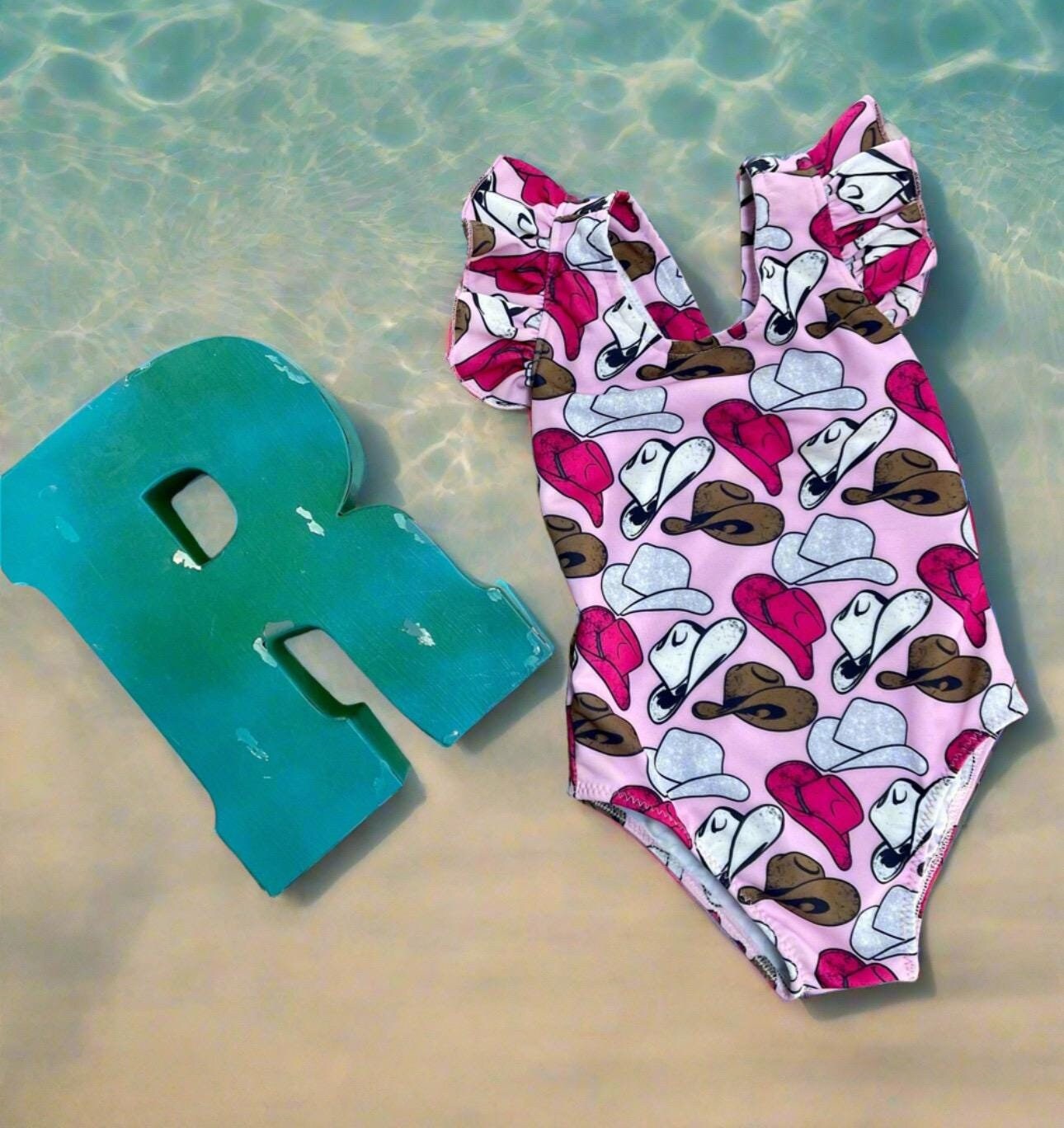 Cowgirl Swimsuit | Pink Cowgirl Hat Swimsuit | Western Swimsuits Girls, Sweetheart of the Rodeo
The cutest Cowgirl Swimsuit is here! Featuring hot pink, silver, and brown cowgirl hats on a bubblegum pink background, this one-piece swimsuit is a must-have for little rodeo queens. The flutter neckline adds the perfect touch of sweetness, making it as adorable as it is stylish!
Ships FREE FROM MONTANA with any $35+ purchase!