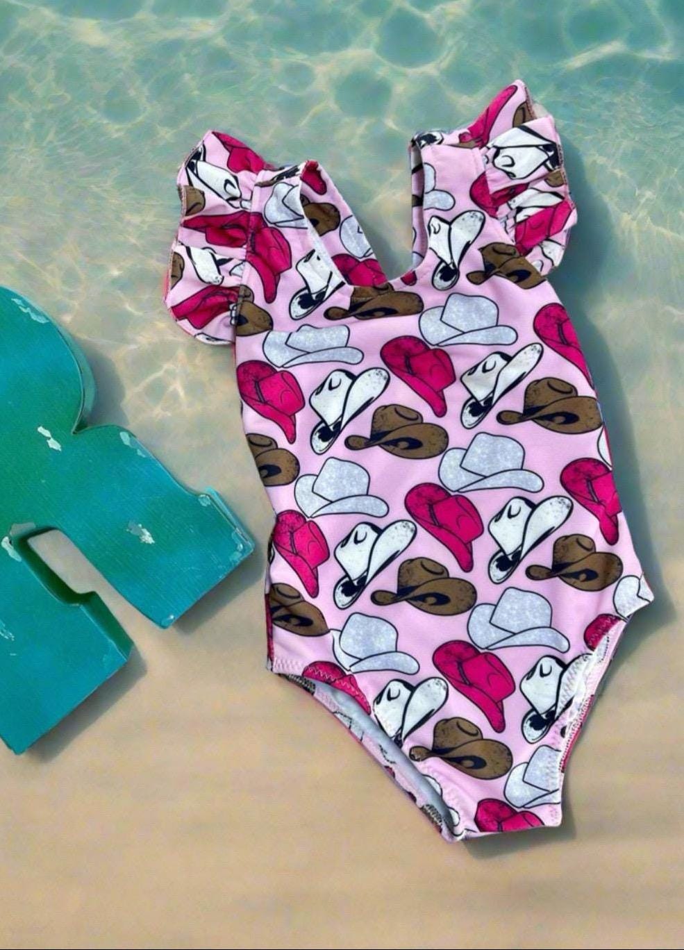 Cowgirl Swimsuit | Pink Cowgirl Hat Swimsuit | Western Swimsuits Girls, Sweetheart of the Rodeo
The cutest Cowgirl Swimsuit is here! Featuring hot pink, silver, and brown cowgirl hats on a bubblegum pink background, this one-piece swimsuit is a must-have for little rodeo queens. The flutter neckline adds the perfect touch of sweetness, making it as adorable as it is stylish!
Ships FREE FROM MONTANA with any $35+ purchase!