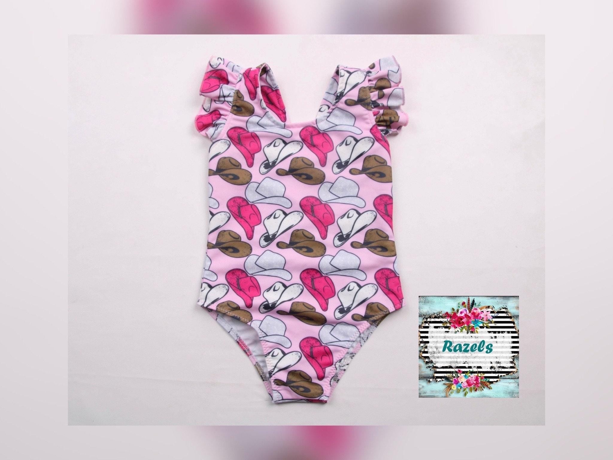 Cowgirl Swimsuit | Pink Cowgirl Hat Swimsuit | Western Swimsuits Girls, Sweetheart of the Rodeo
The cutest Cowgirl Swimsuit is here! Featuring hot pink, silver, and brown cowgirl hats on a bubblegum pink background, this one-piece swimsuit is a must-have for little rodeo queens. The flutter neckline adds the perfect touch of sweetness, making it as adorable as it is stylish!
Ships FREE FROM MONTANA with any $35+ purchase!