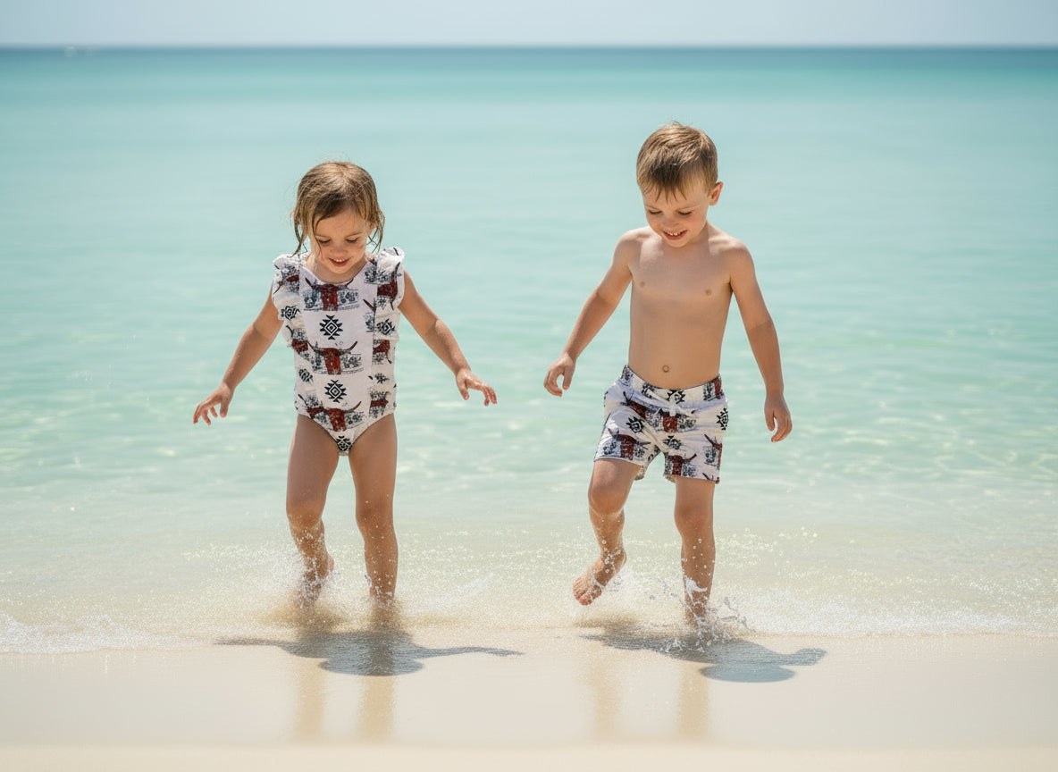 Western Swimsuits – Longhorn Steer Sibling Swimsuits. Get ready for summer with these Matching Swimsuits featuring a bold Longhorn Steer design! This black-and-white desert scene with a geometric touch is perfect for little cowboys and cowgirls who love Western style.
Cowboy Swim Trunks: Unlined for comfort, with a functional drawstring—also great as stylish day shorts!
Cowgirl Swimsuit: An adorable one-piece swimsuit with front ruffles fit for little rodeo queens!