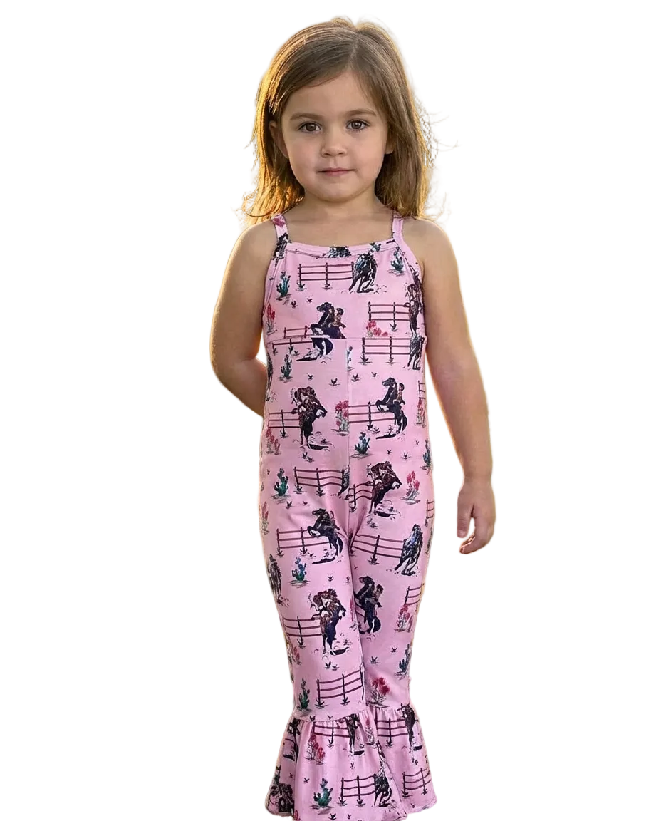 Young girl wearing a pink romper with retro cowgirl print allover standing in a field