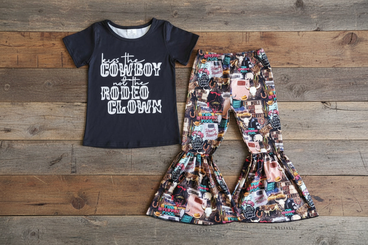 Black t-shirt with text and colorful patterned pants on a textured surface