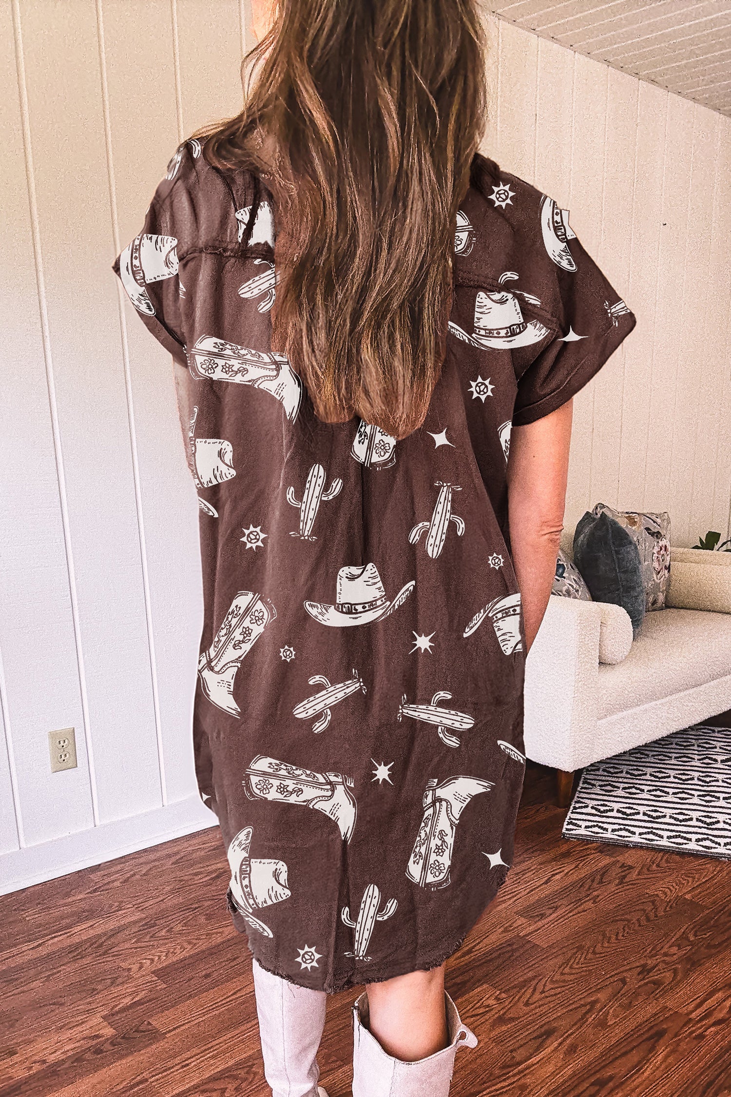 Person wearing a brown dress with white cowboy boots, cacti patterns in a living room.