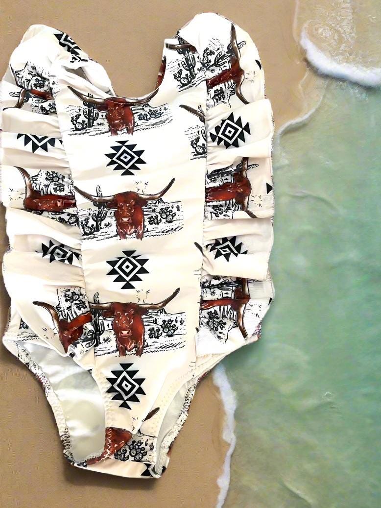 Western Swimsuits – Longhorn Steer Sibling Swimsuits. Get ready for summer with these Matching Swimsuits featuring a bold Longhorn Steer design! This black-and-white desert scene with a geometric touch is perfect for little cowboys and cowgirls who love Western style.
Cowboy Swim Trunks: Unlined for comfort, with a functional drawstring—also great as stylish day shorts!
Cowgirl Swimsuit: An adorable one-piece swimsuit with front ruffles fit for little rodeo queens!