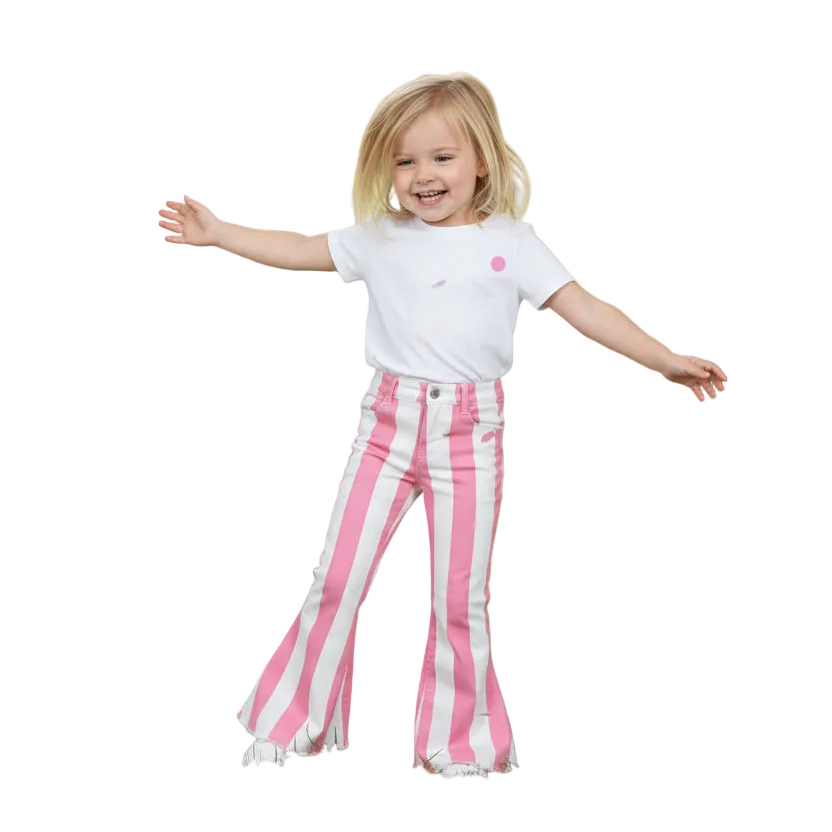 A young girl with blonde hair is smiling and posing with her arms outstretched, wearing a white t-shirt and pink and white vertically striped flared jeans, isolated on a white background.