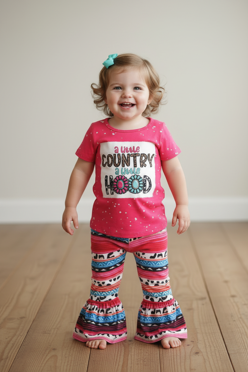 baby girl wearing a pink outfit with 'A Little Country, A Little Hood' text on a wooden floor.