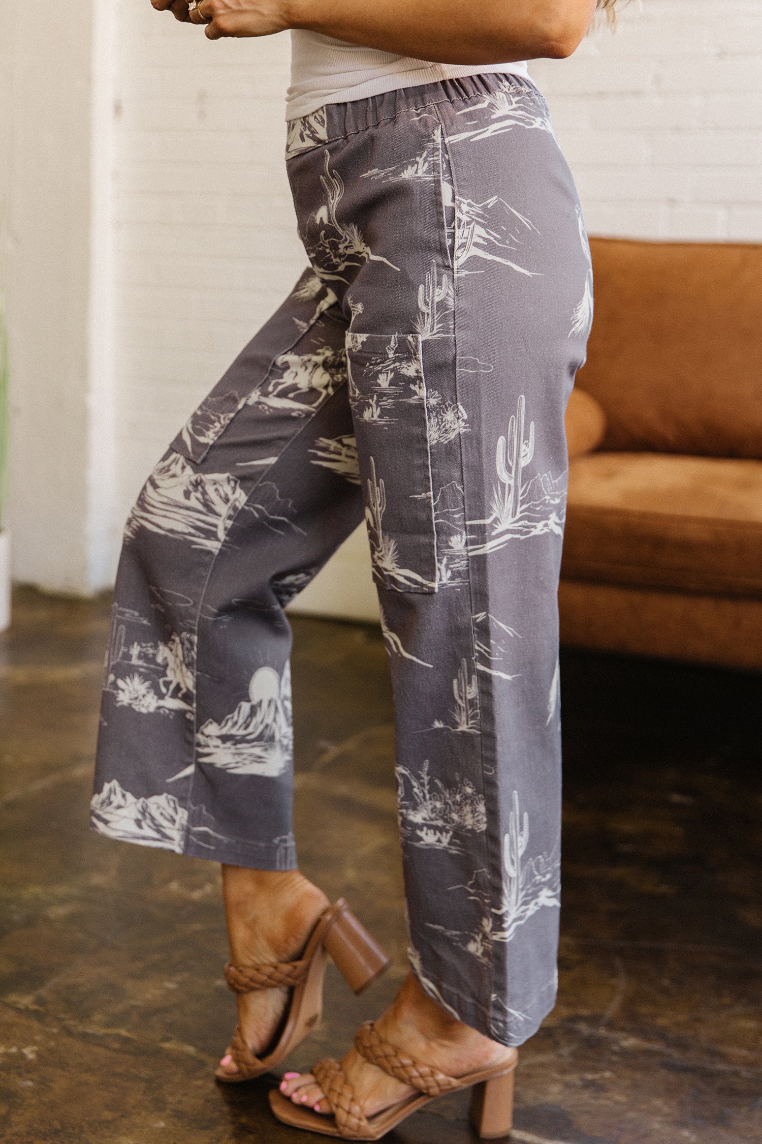 Person wearing gray pants with white white cowboy desert in a casual setting.