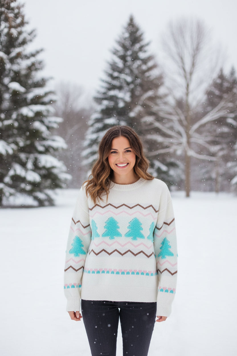 White sweater with blue tree patterns and brown zigzag lines on a white background